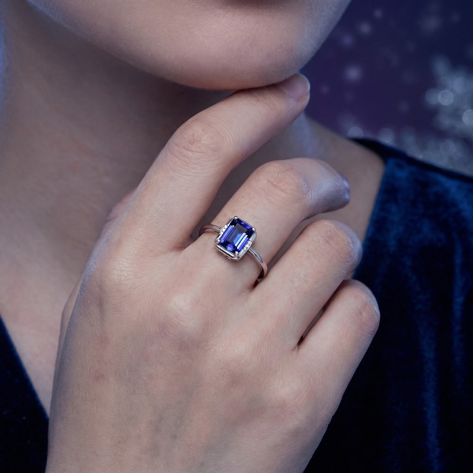 Emerald-cut simulated tanzanite sterling silver ring worn on a woman's hand to show scale and finger fit.