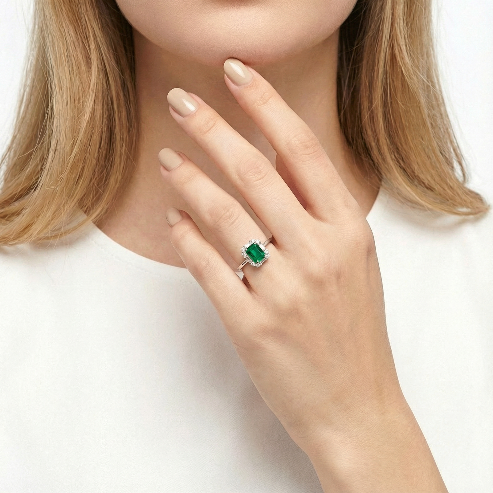 Model wearing the octagon simulated emerald halo ring in sterling silver on her ring finger against a white shirt.