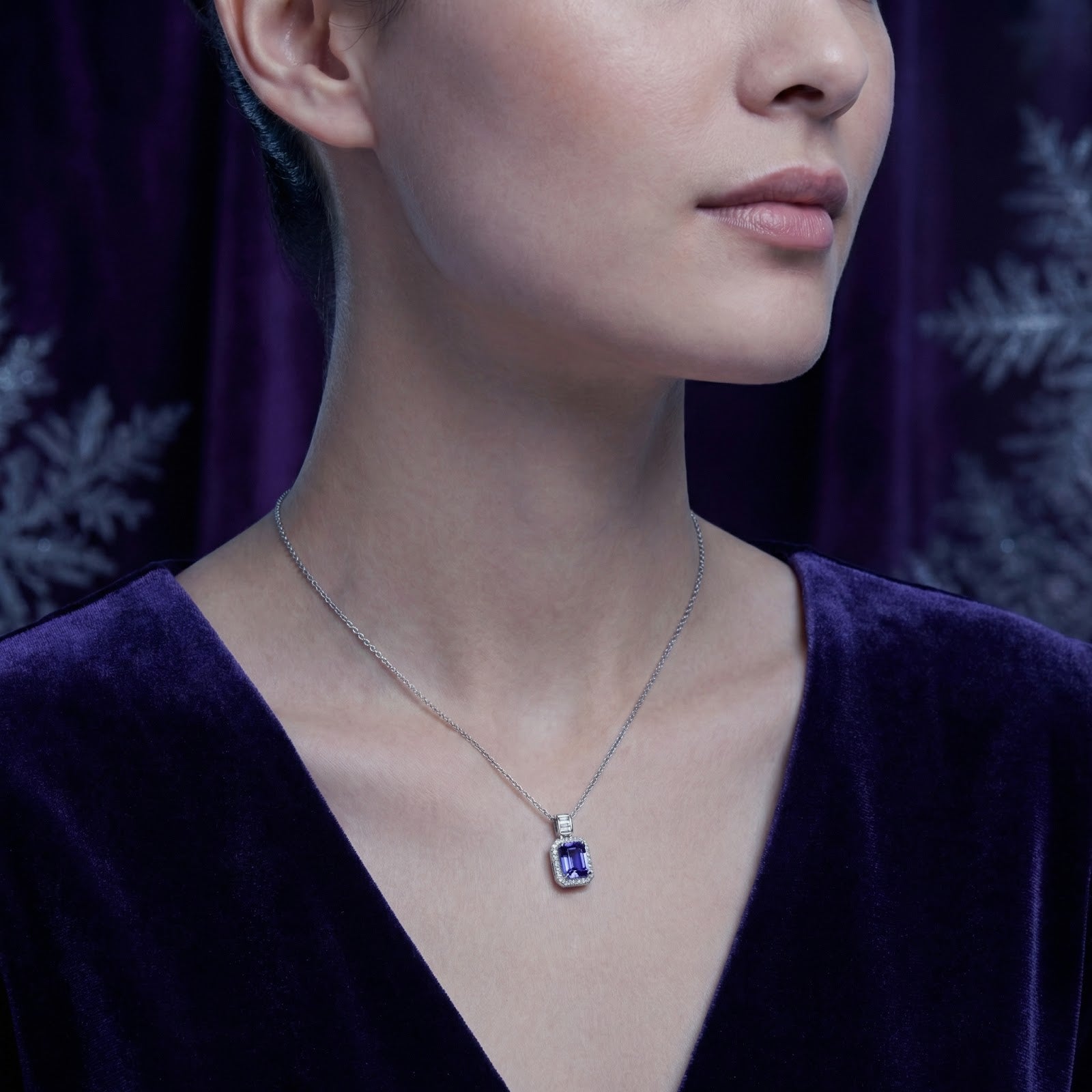 Model wearing the Myrenne simulated tanzanite pendant in sterling silver, styled with a purple velvet dress.