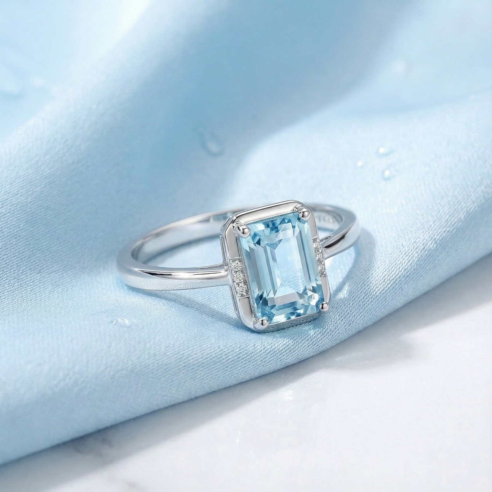 Emerald cut simulated aquamarine ring in sterling silver on a light blue silk background.