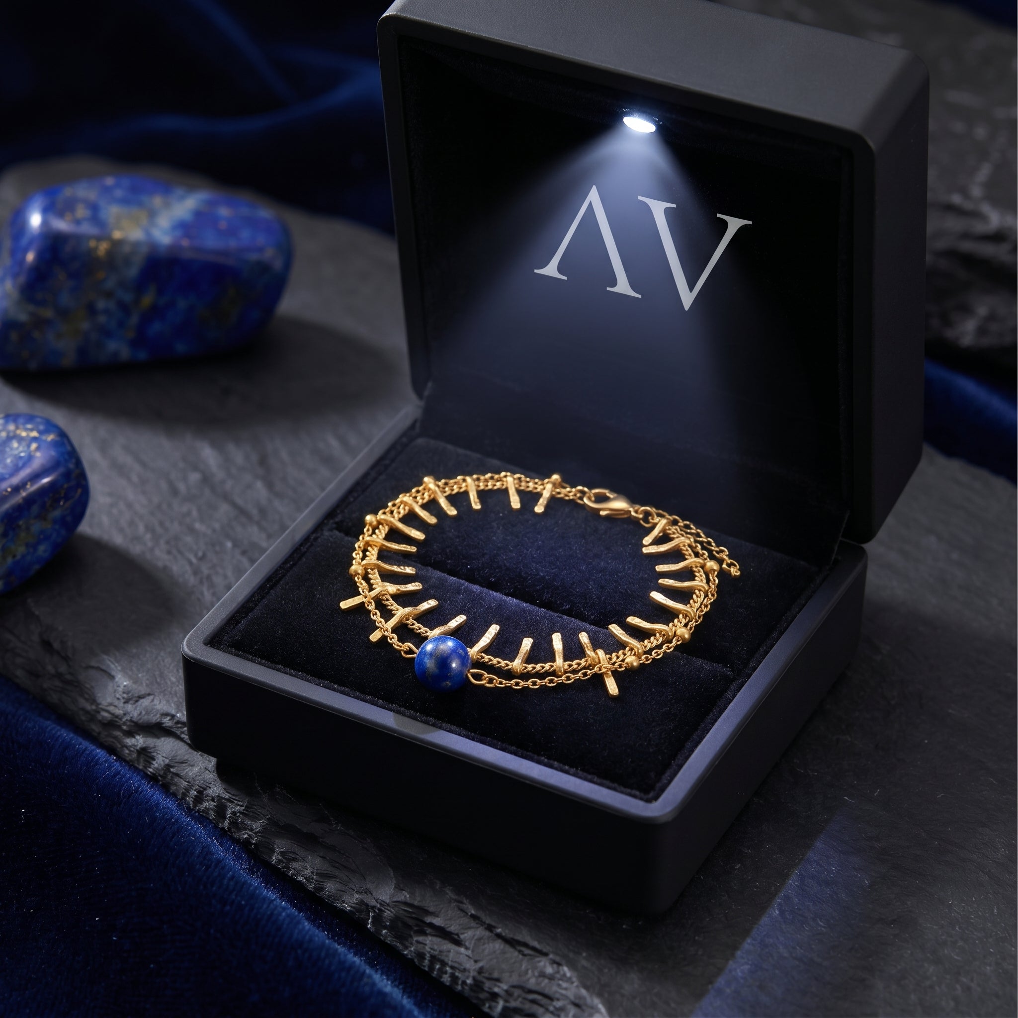 18K gold plated lapis lazuli bracelet inside a black lighted jewelry box with a silver AV logo.