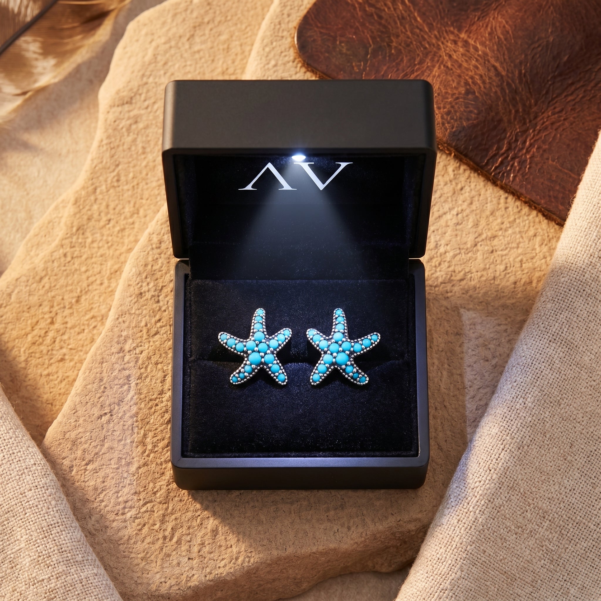 Sterling silver turquoise starfish earrings presented in a black LED-lighted jewelry gift box.