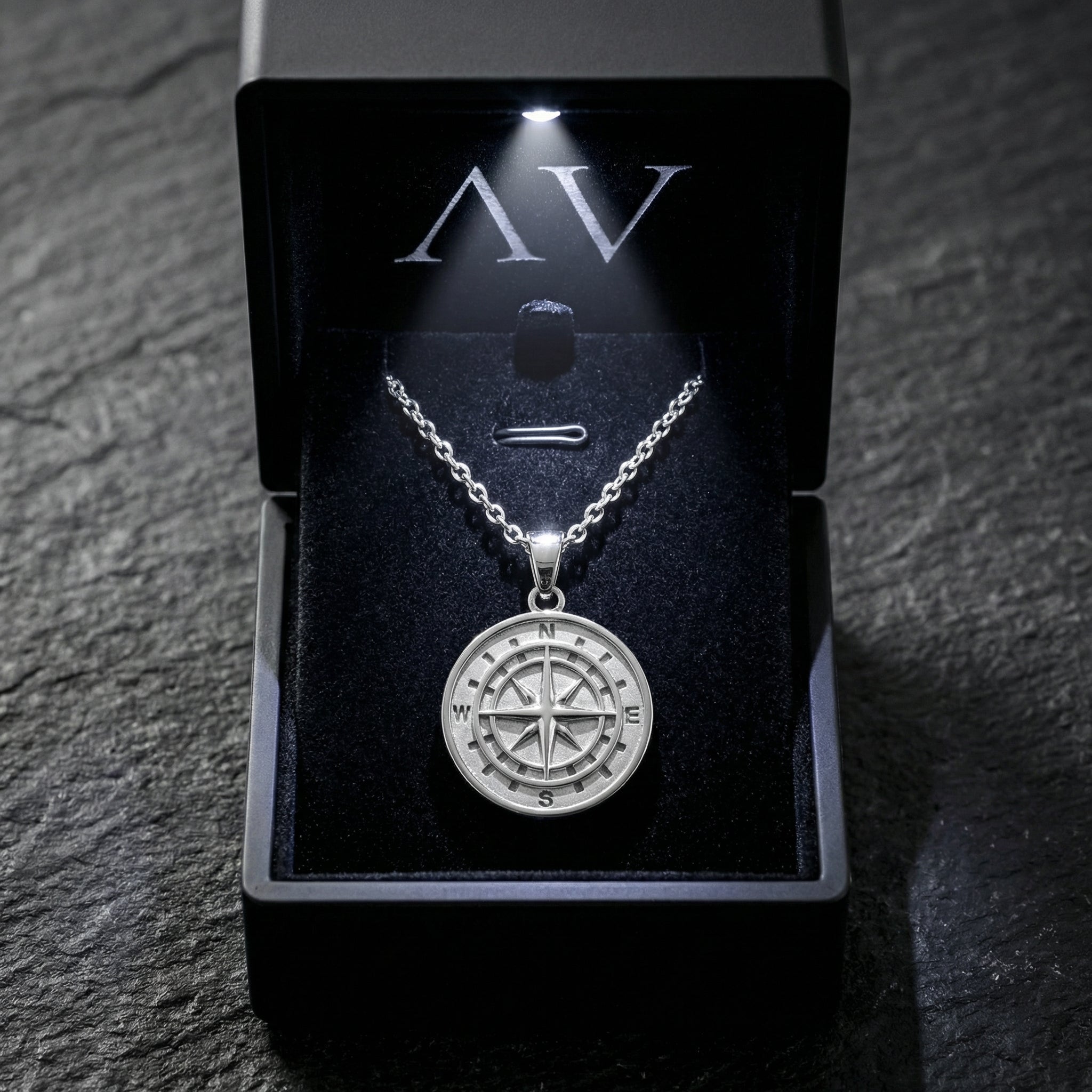 Silver stainless steel compass pendant necklace presented in a black illuminated gift box.