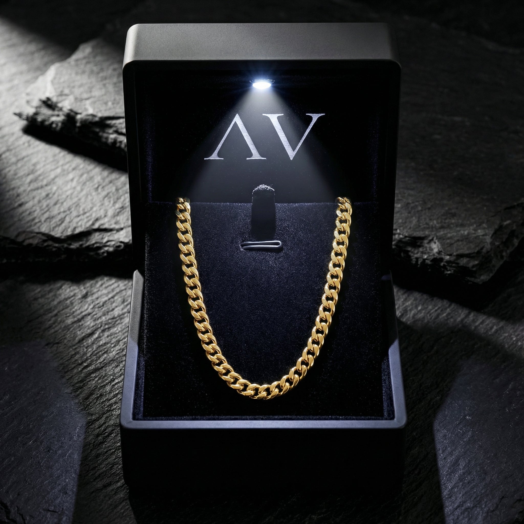 4mm gold stainless steel Cuban chain necklace presented in a black LED-lit jewelry box on a stone background.