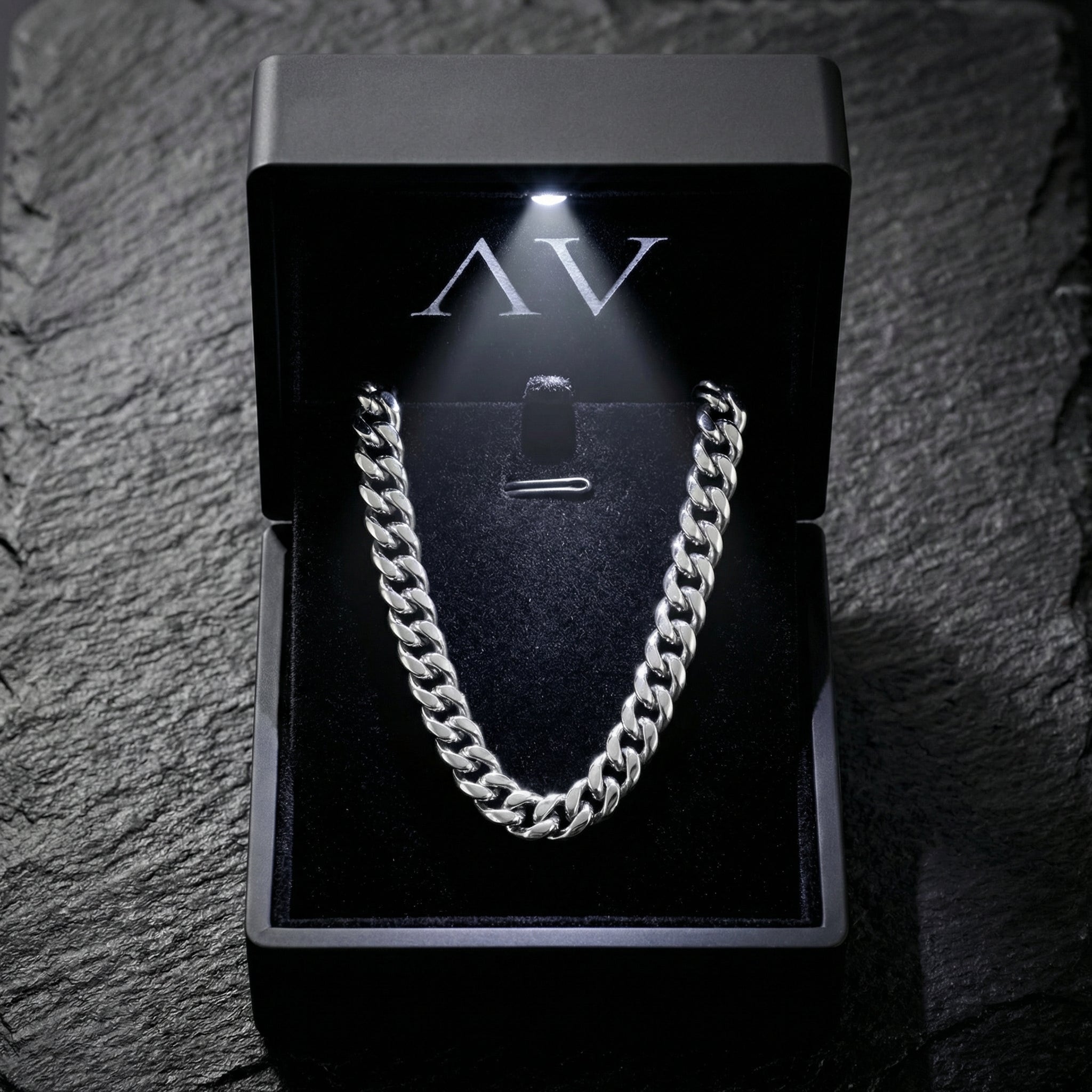 Silver 8mm stainless steel Cuban chain inside a black LED-lit jewelry box on a stone surface.