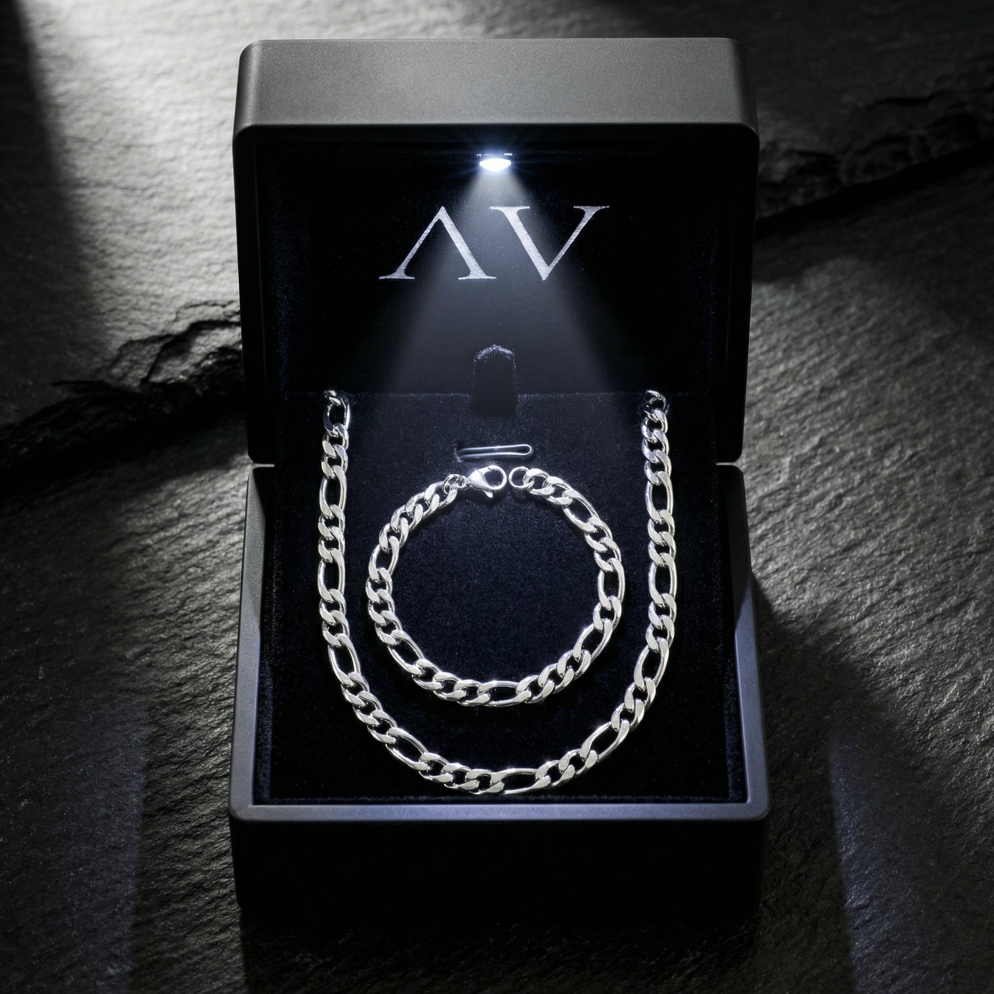 Polished silver Figaro chain and bracelet set presented in a premium black LED-lit jewelry gift box.