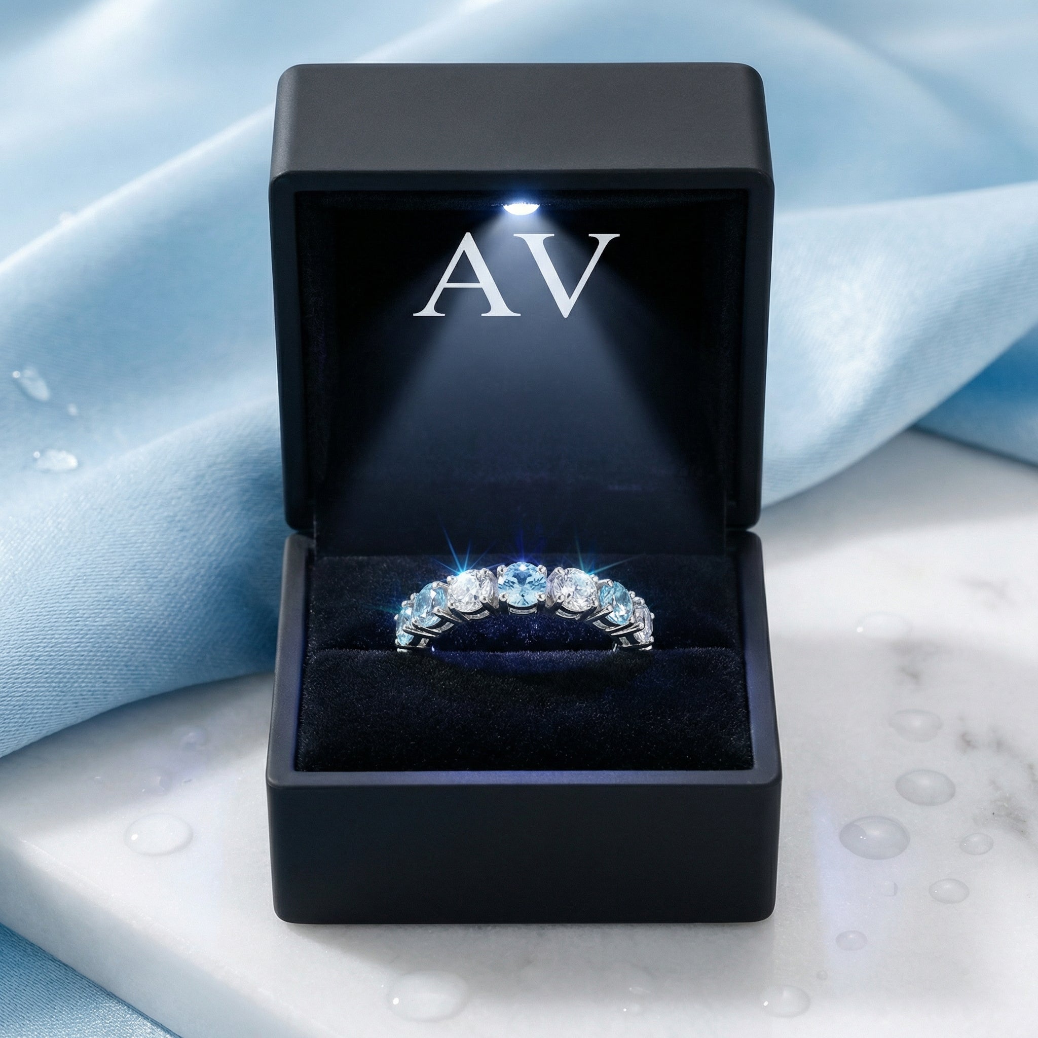 Sterling silver simulated aquamarine eternity band displayed in a black lighted jewelry gift box.