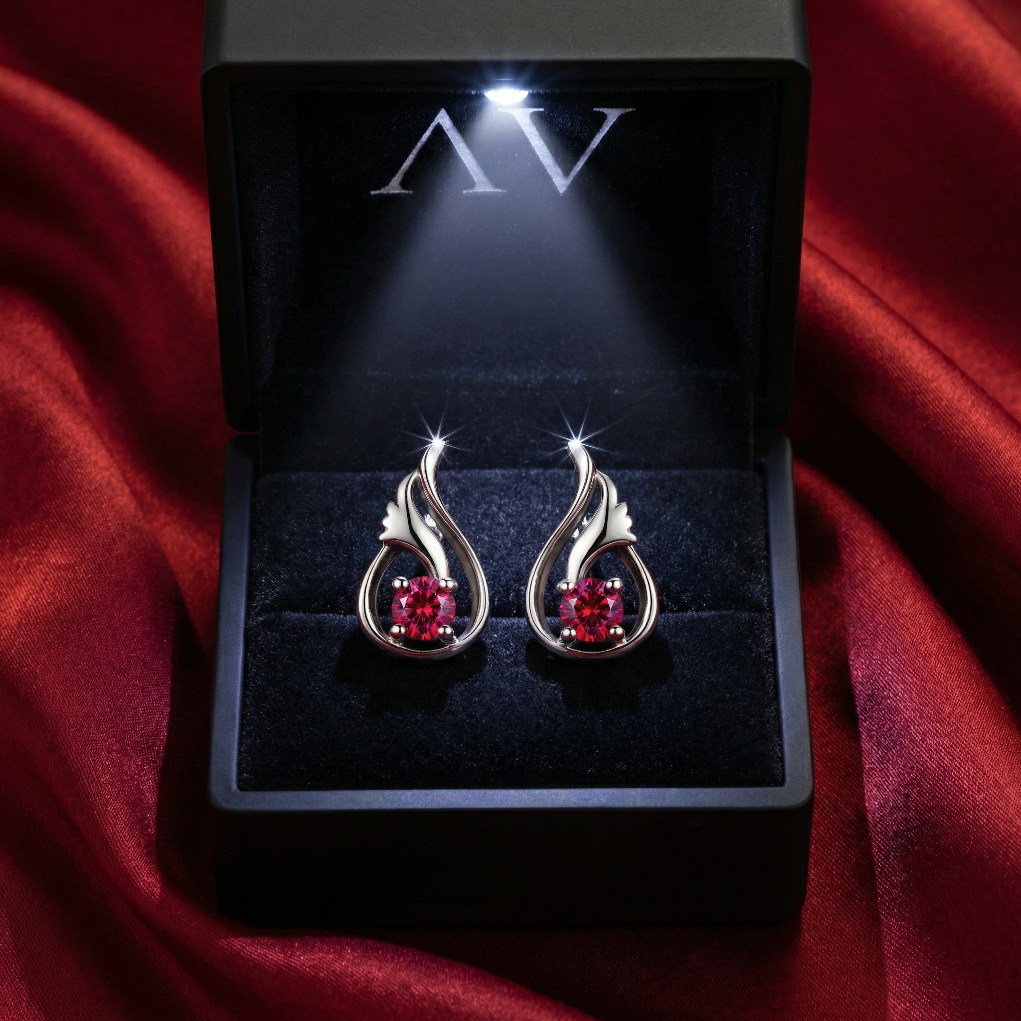Round cut simulated ruby sterling silver earrings presented in a lighted black jewelry gift box.