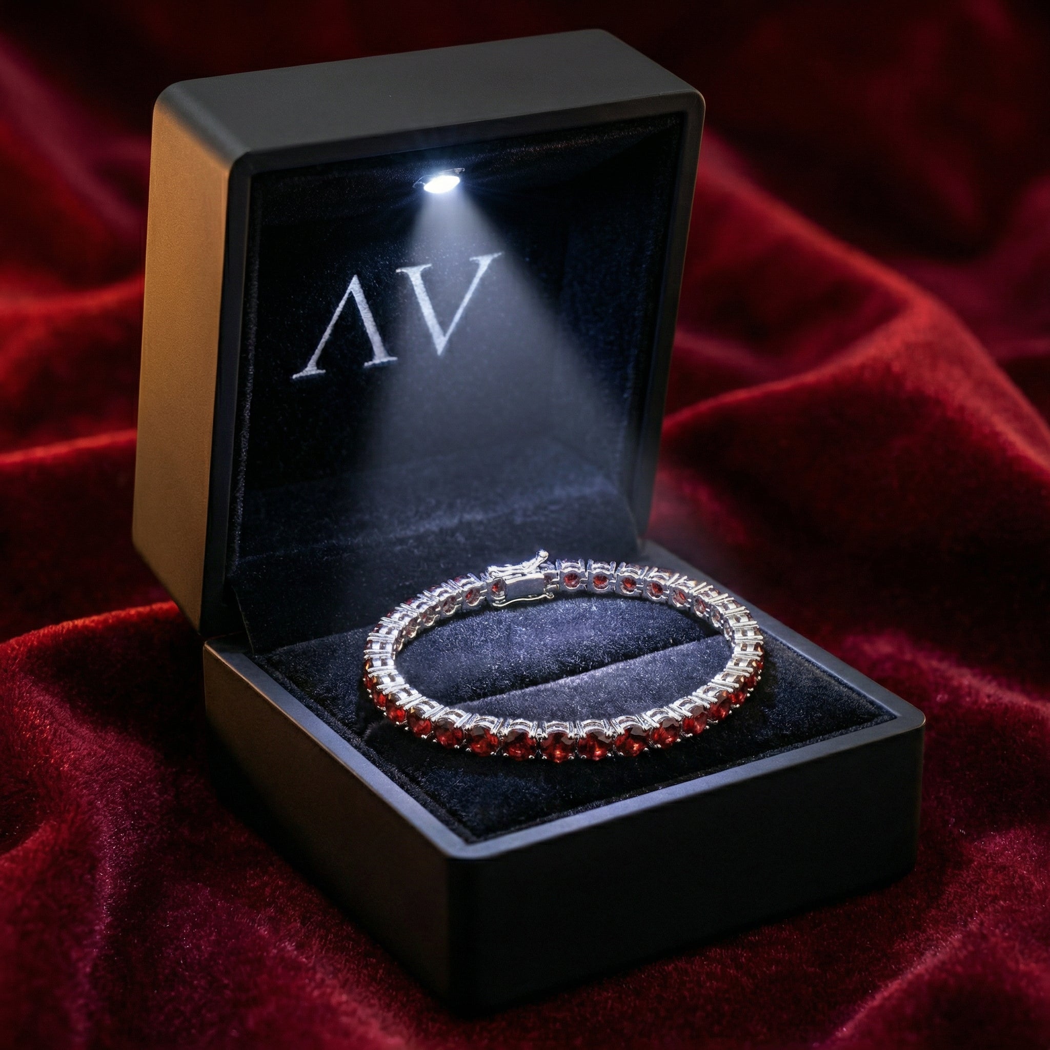 Stainless steel red garnet tennis bracelet inside a black LED-lit presentation box on red velvet.