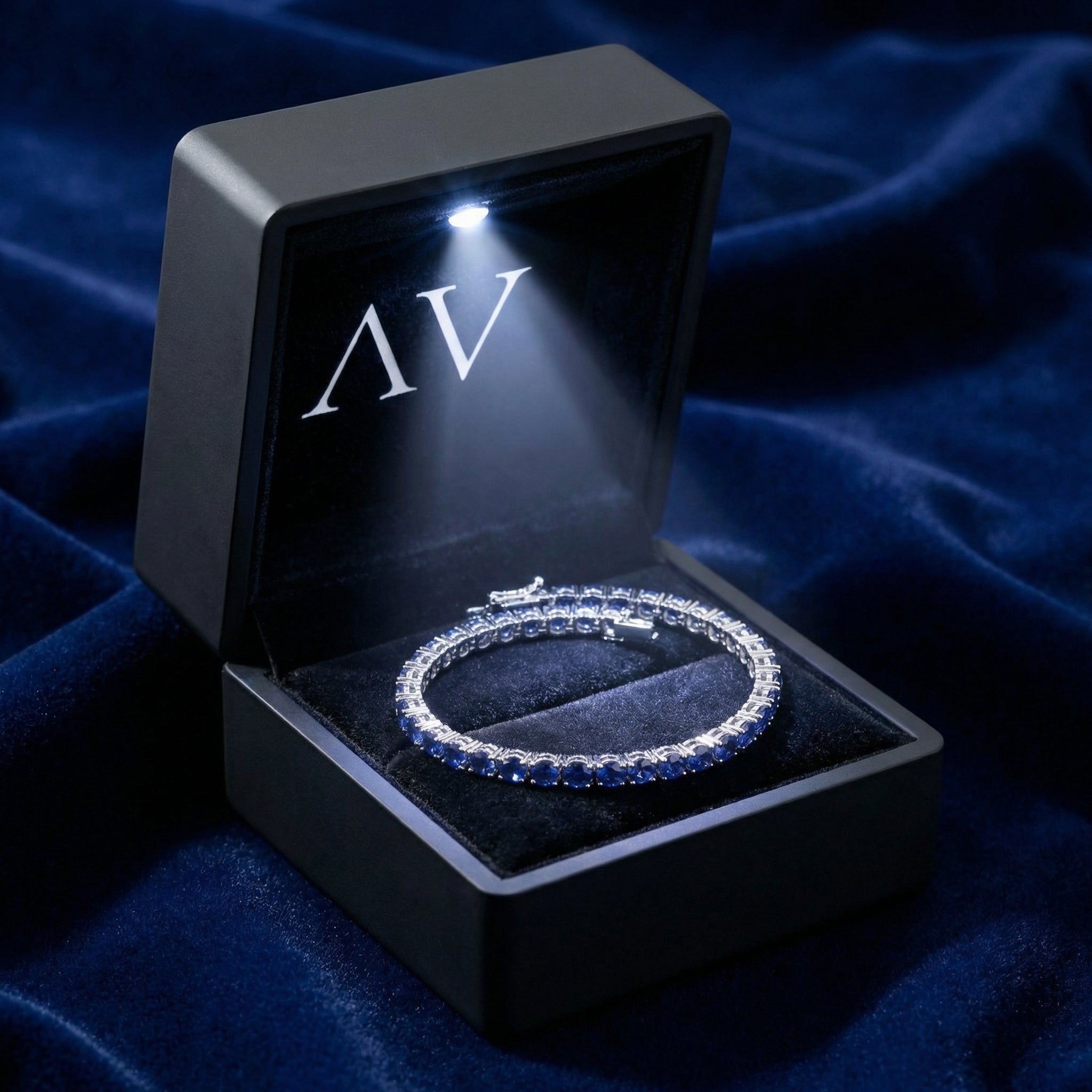Silver stainless steel royal blue sapphire tennis bracelet inside a black LED-lighted jewelry gift box.