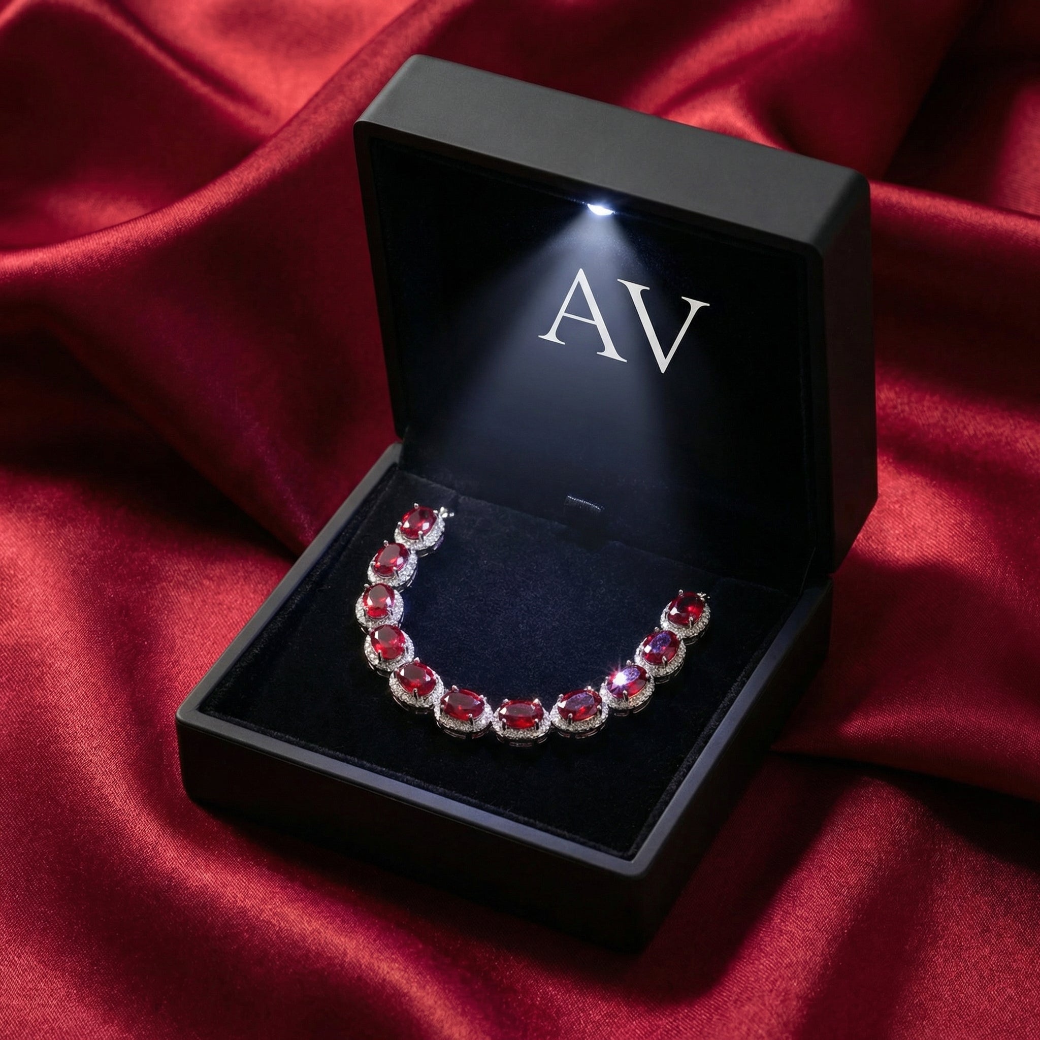 Simulated ruby tennis bracelet in sterling silver presented in a lighted black AV jewelry gift box.