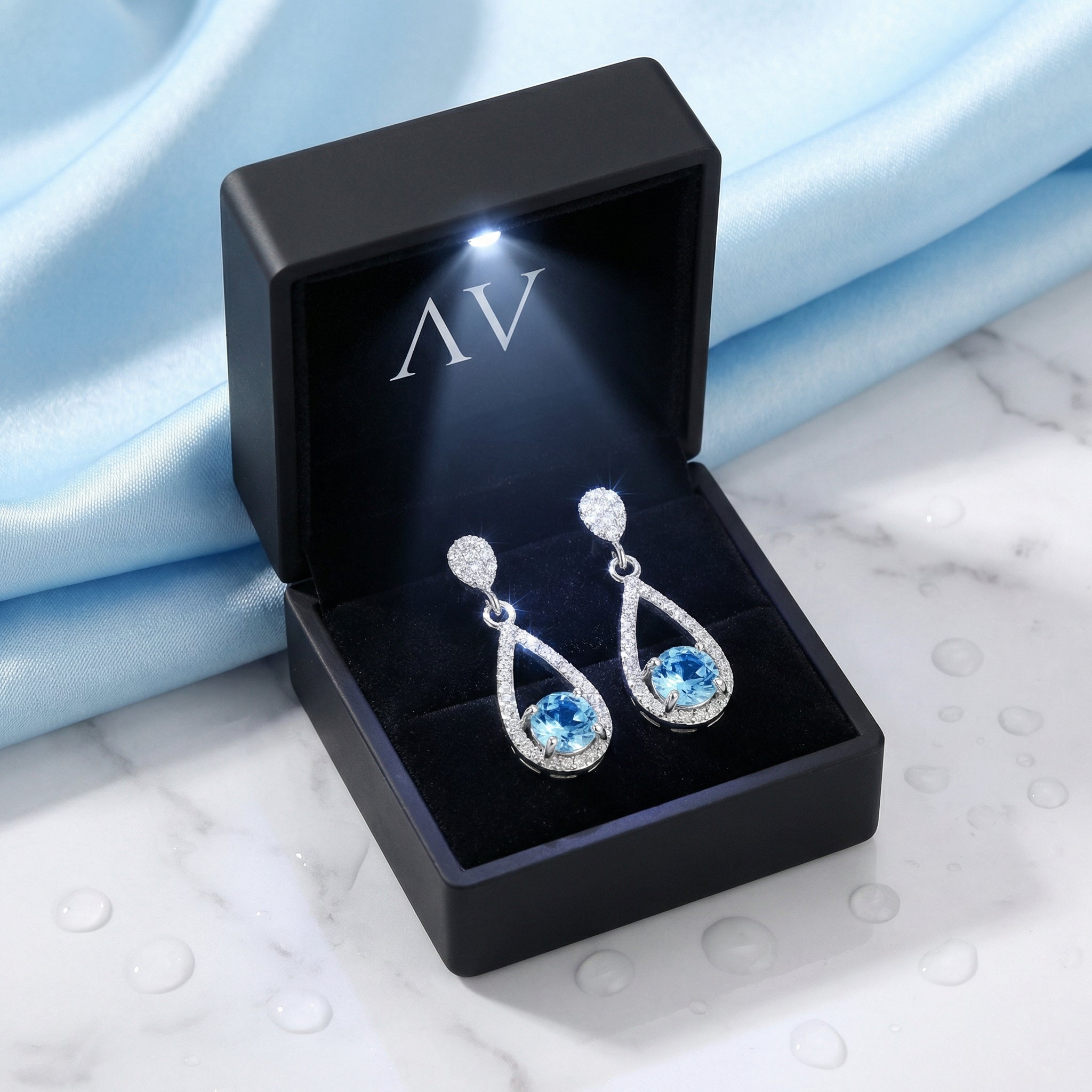 Sterling silver simulated aquamarine drop earrings displayed in a black LED-lit jewelry presentation box.