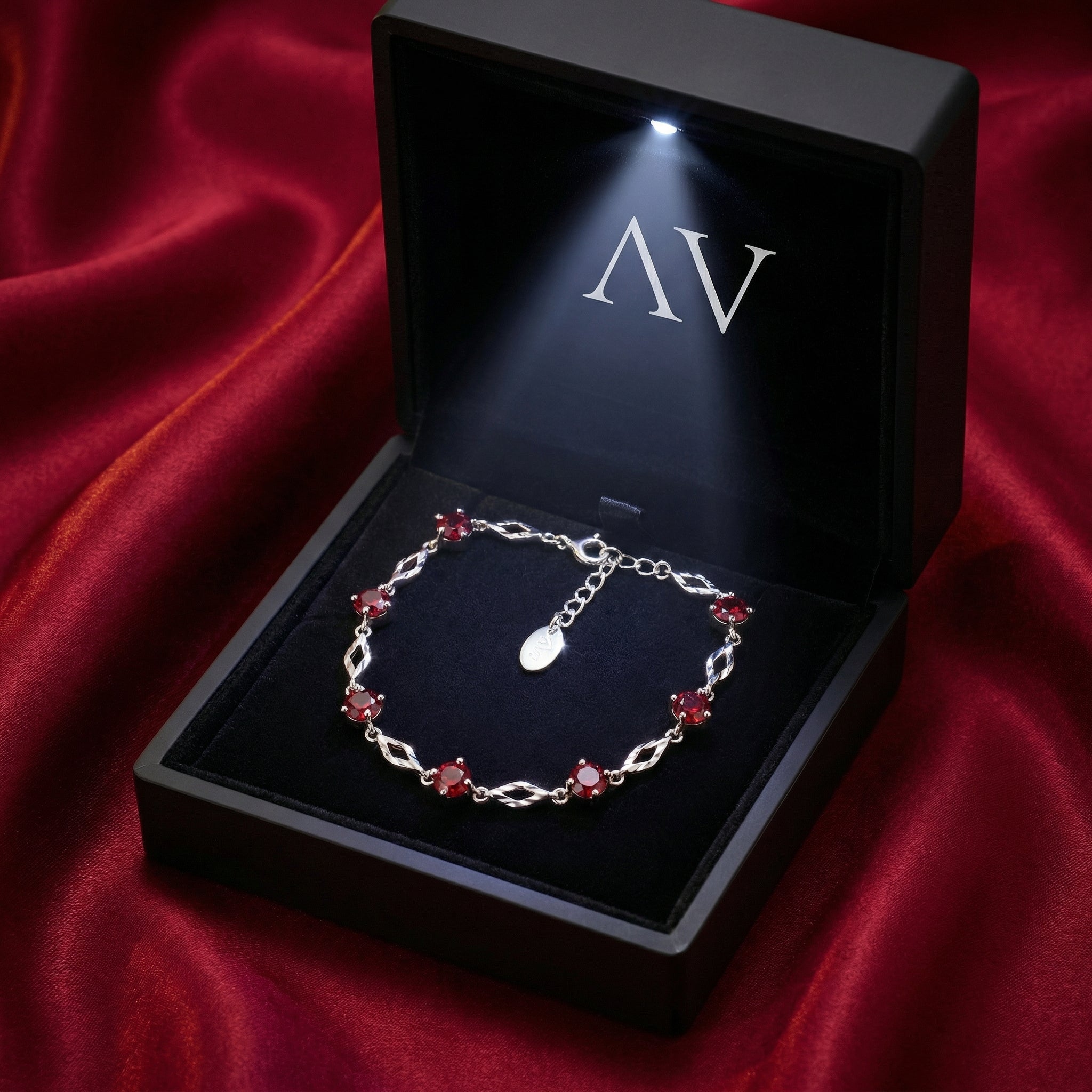 Sterling silver simulated ruby station bracelet inside a black LED-lit jewelry gift box on red silk.