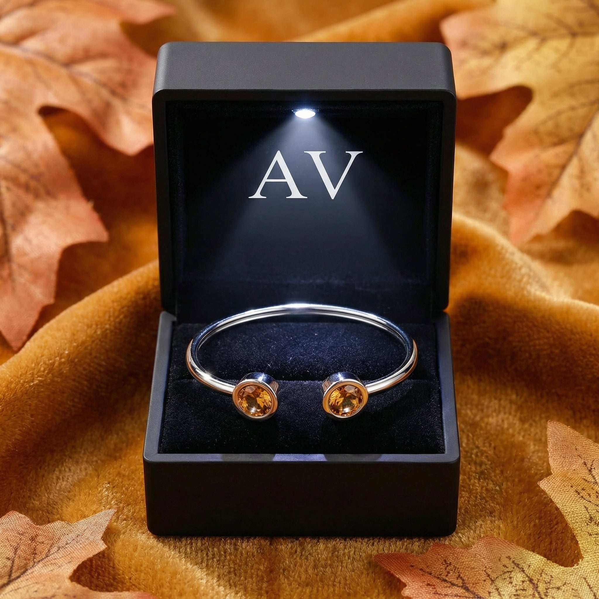 Silver stainless steel Vesperelle cuff with simulated topaz stones in a black LED-lit branded jewelry gift box.