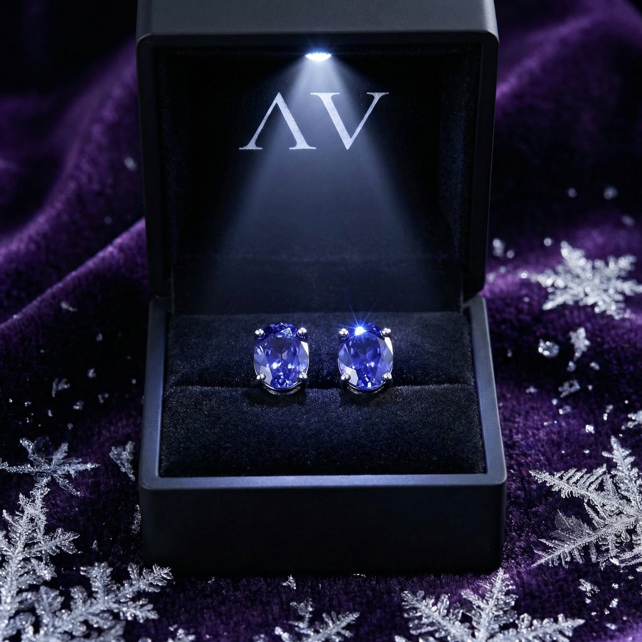 Oval cut simulated tanzanite stud earrings in sterling silver inside a lighted black jewelry gift box.