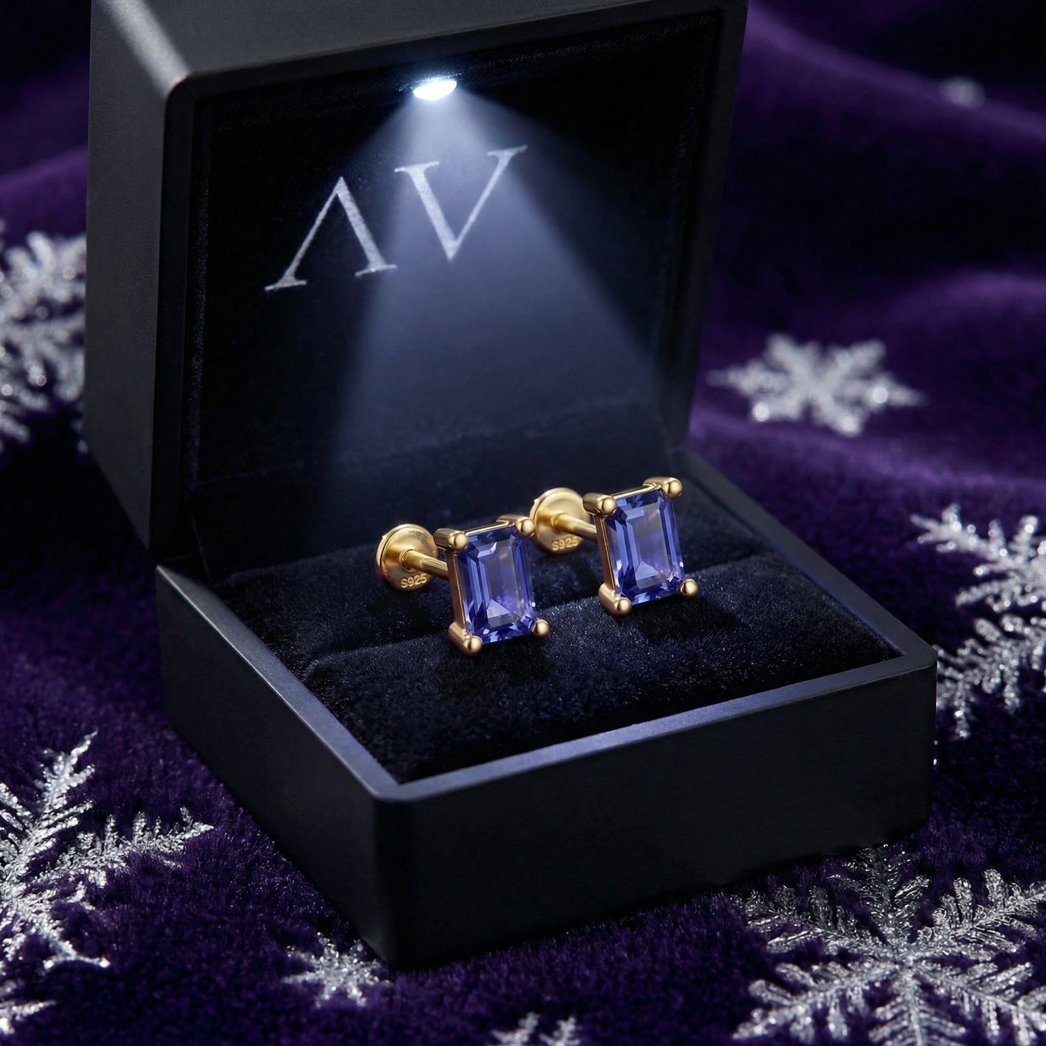 Emerald-cut simulated tanzanite stud earrings in 18K gold vermeil presented in a lighted black AV jewelry box.