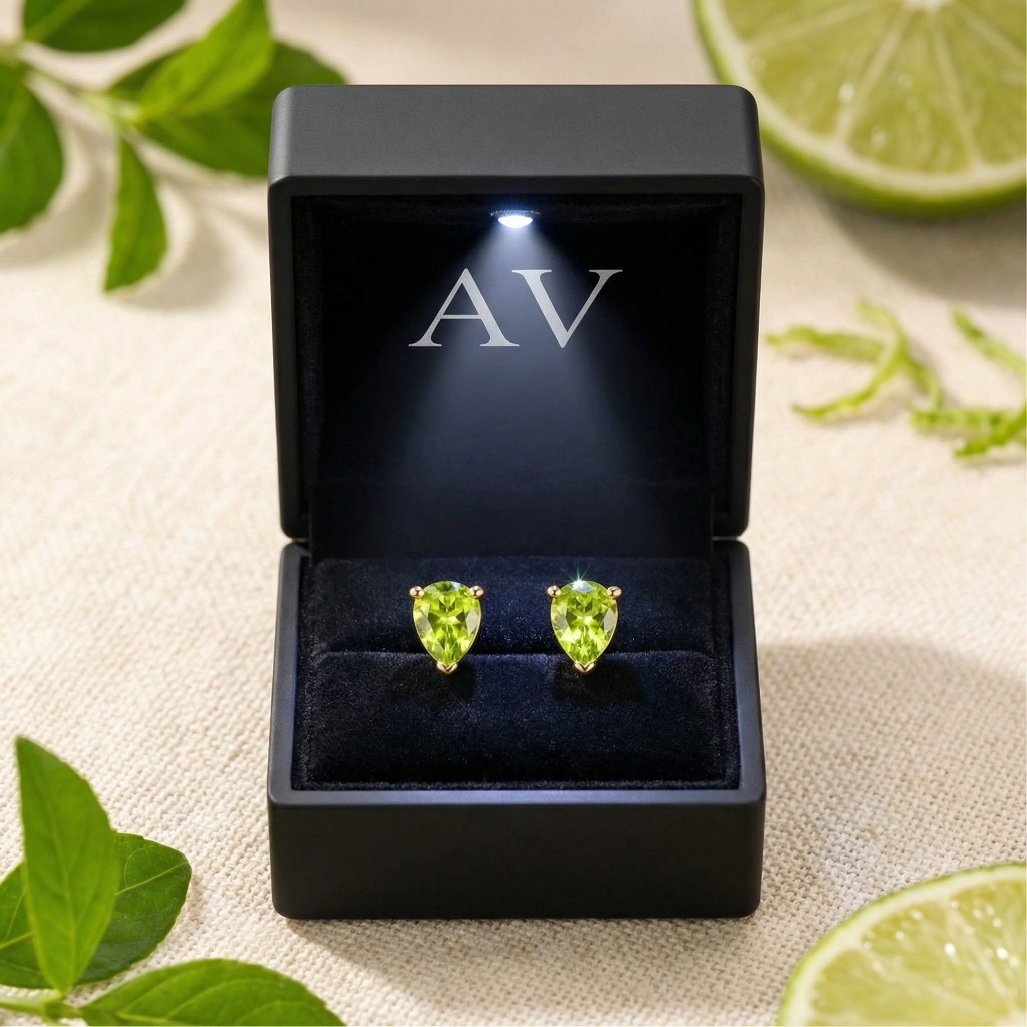 Pear-cut simulated peridot stud earrings in 18K gold vermeil inside a black LED-lit jewelry presentation box.