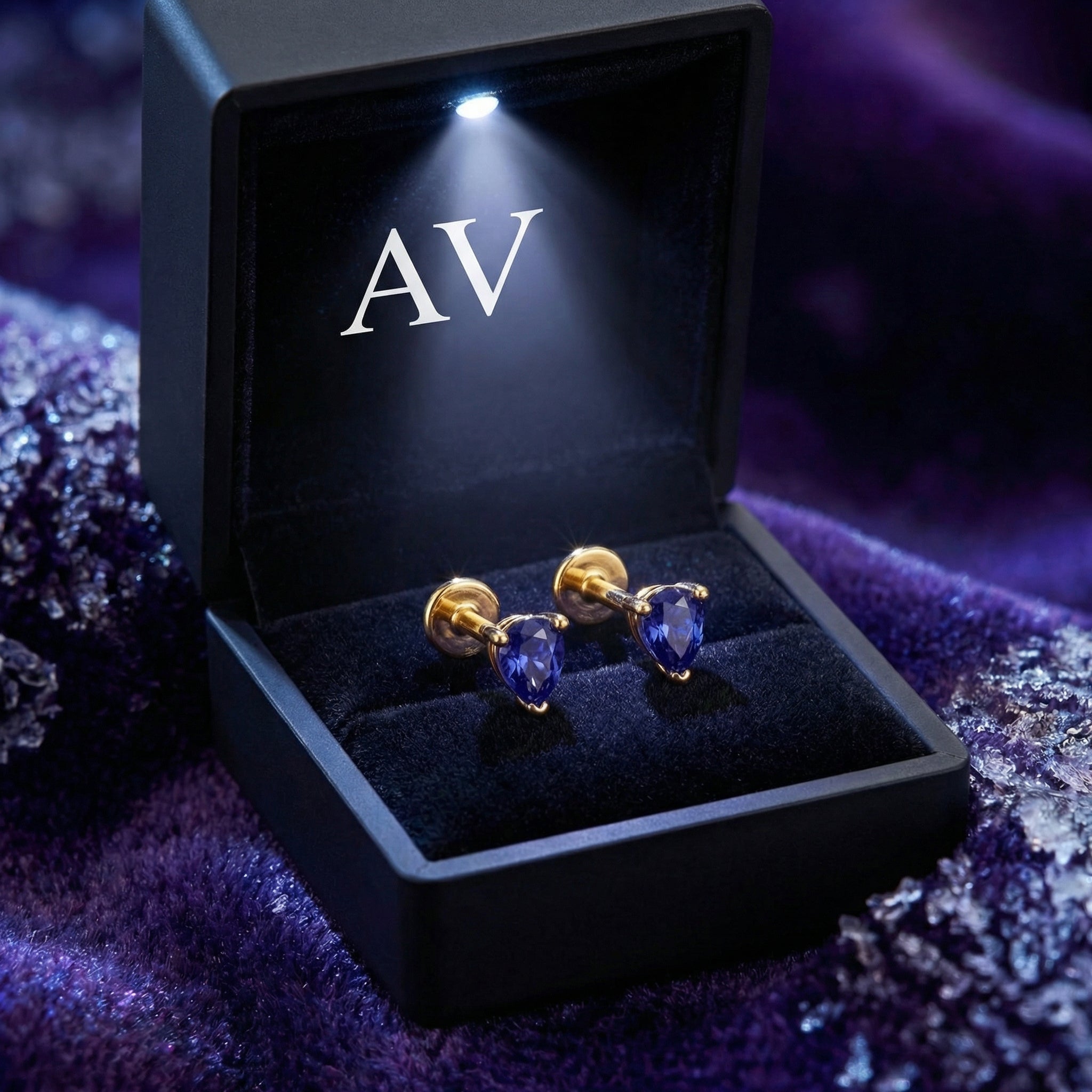 Pair of pear-cut simulated tanzanite earrings in 18K gold vermeil inside a lighted black AV jewelry box.