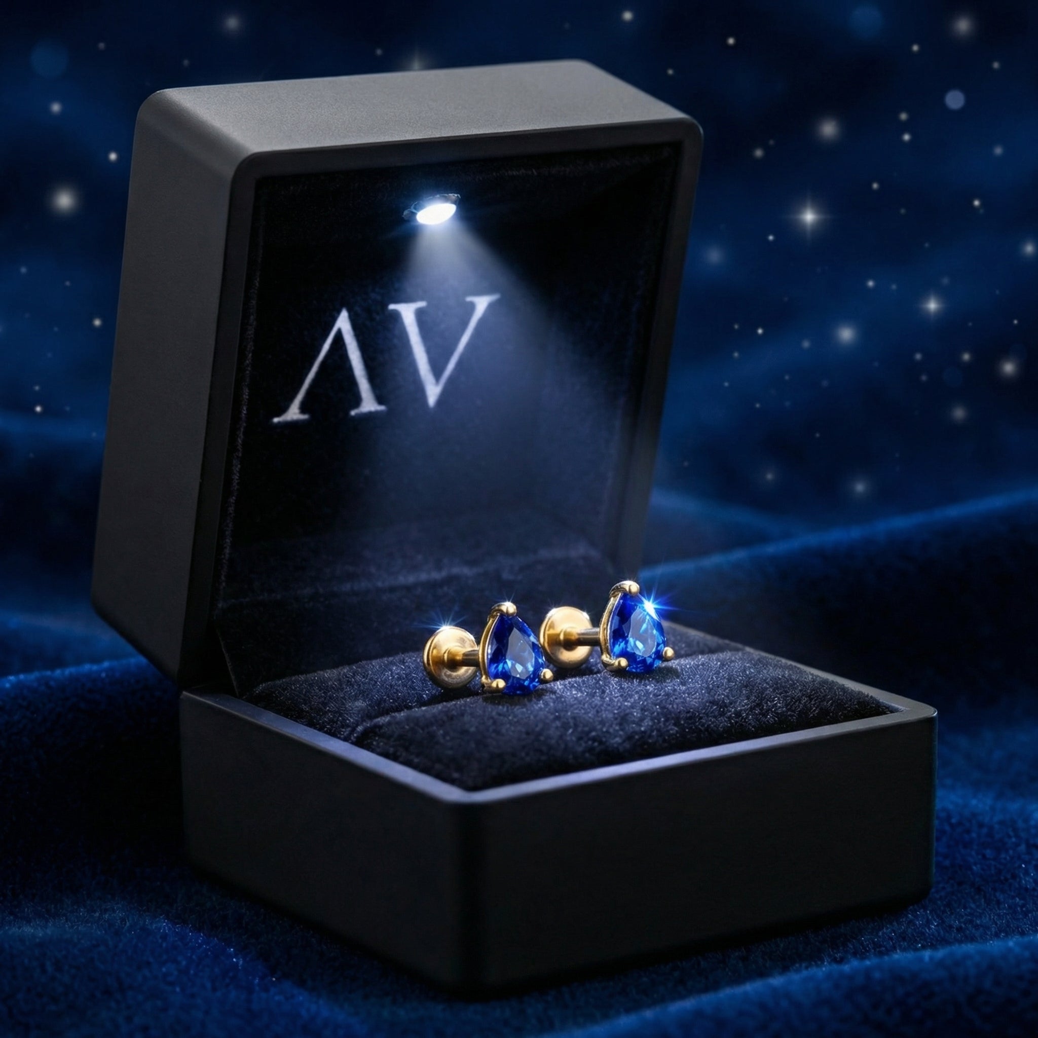 Pear-cut simulated sapphire stud earrings in 18K gold vermeil inside a lighted black jewelry box.