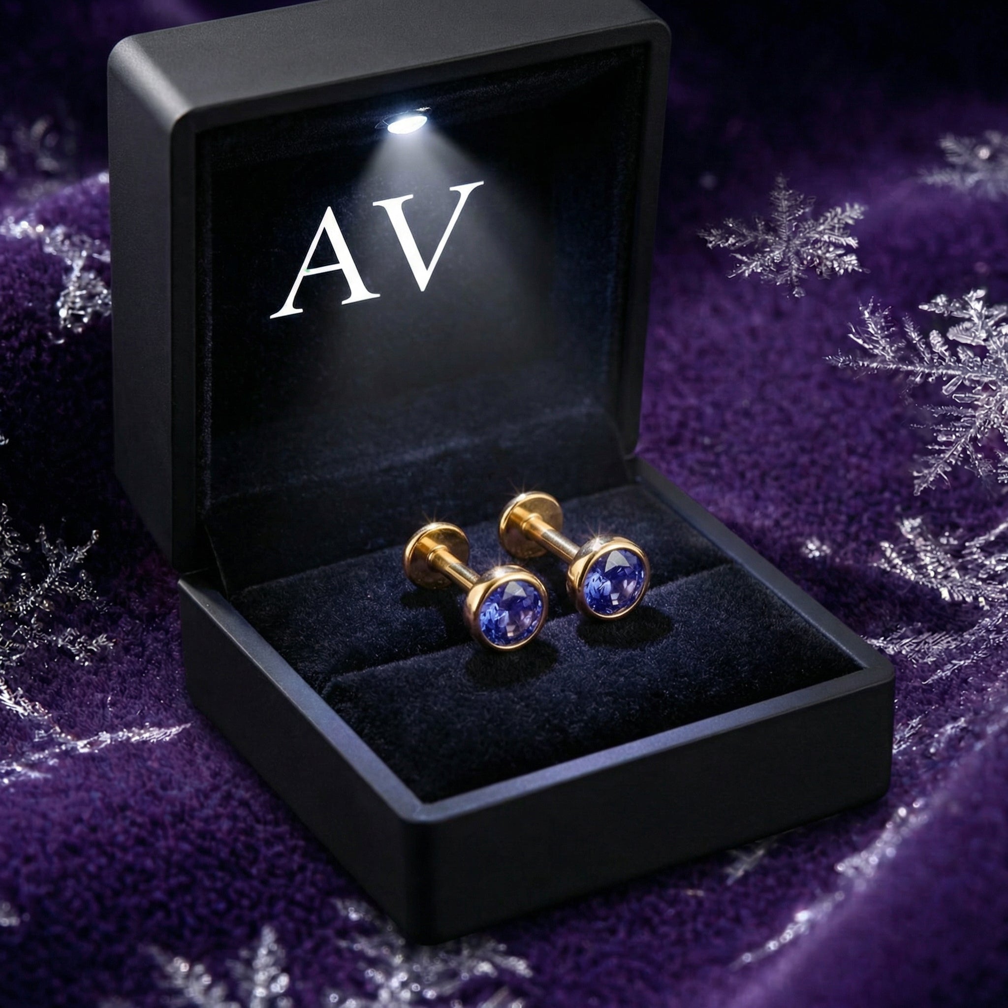 Gold vermeil simulated tanzanite stud earrings in a black lighted jewelry box with AV branding.