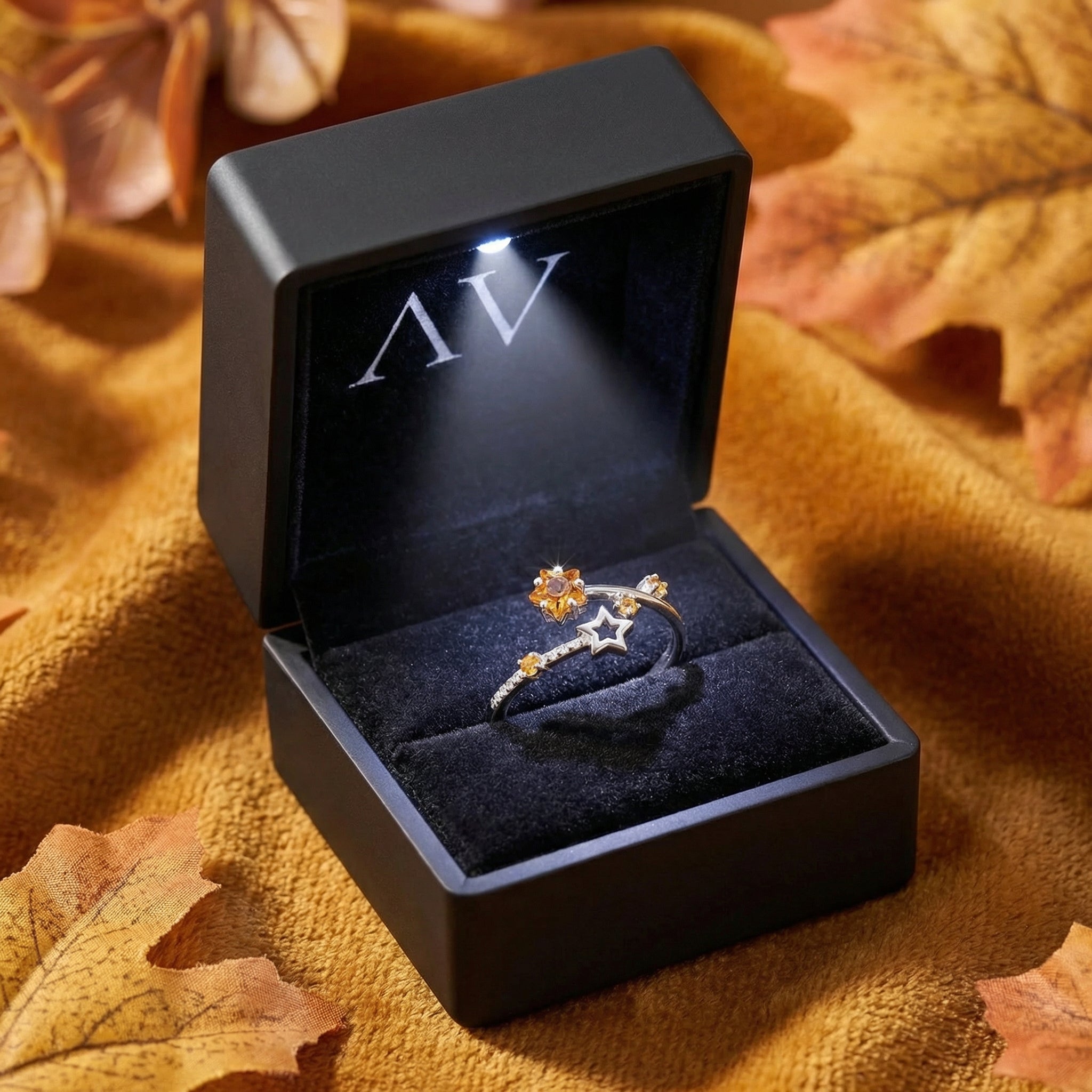 Silver Astralis Star ring with simulated topaz displayed in a black LED-lit jewelry gift box on an autumn background.