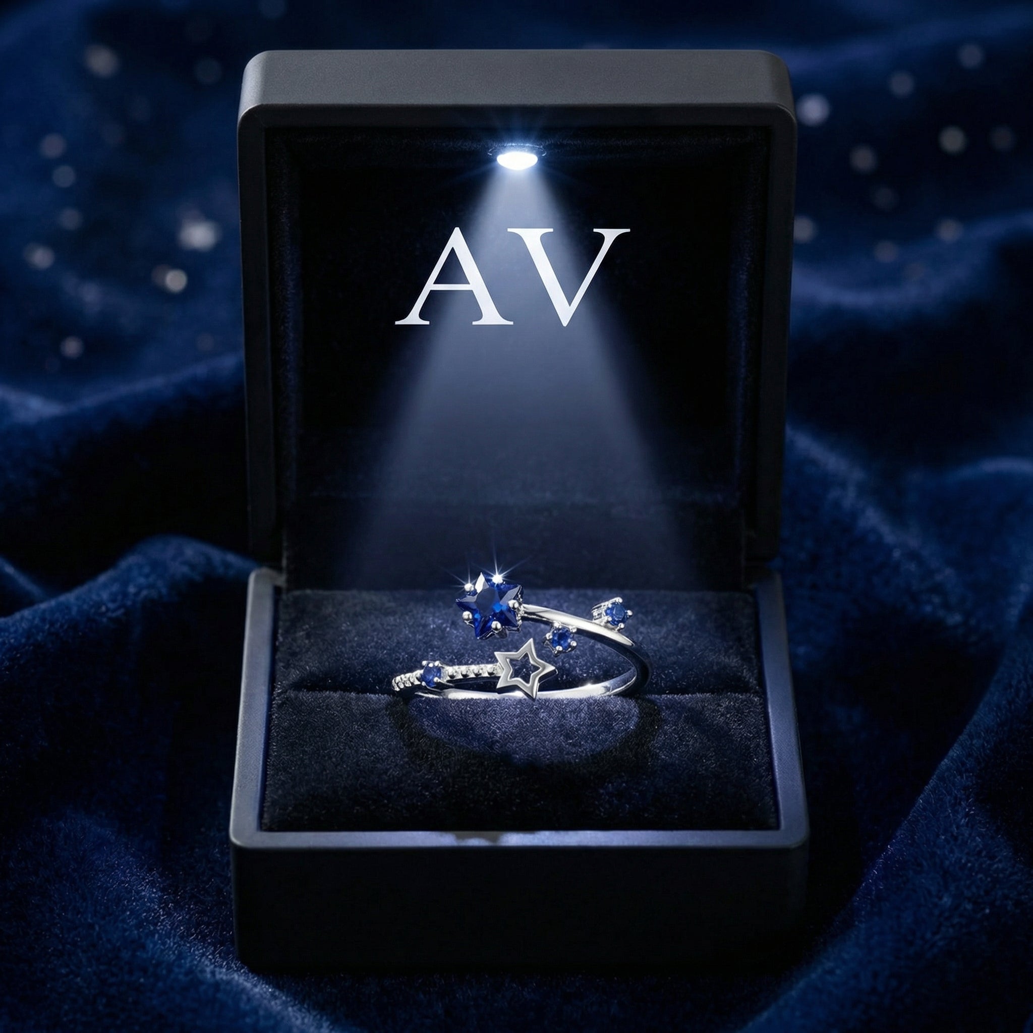 The Orionis star ring presented in a black LED-lit jewelry box on a blue velvet surface.