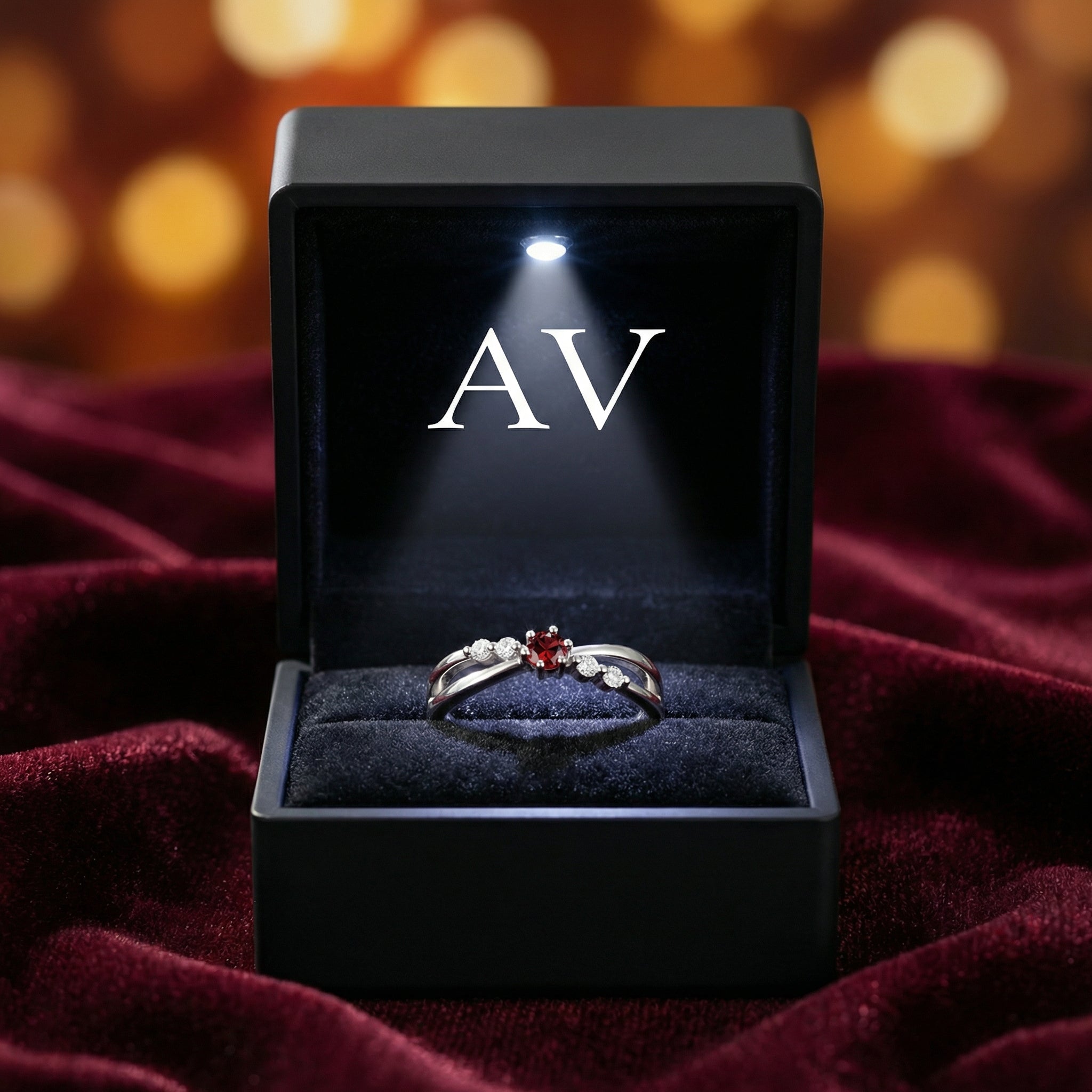 Sterling silver bypass ring with red garnet in a black lighted gift box with AV logo on red velvet.