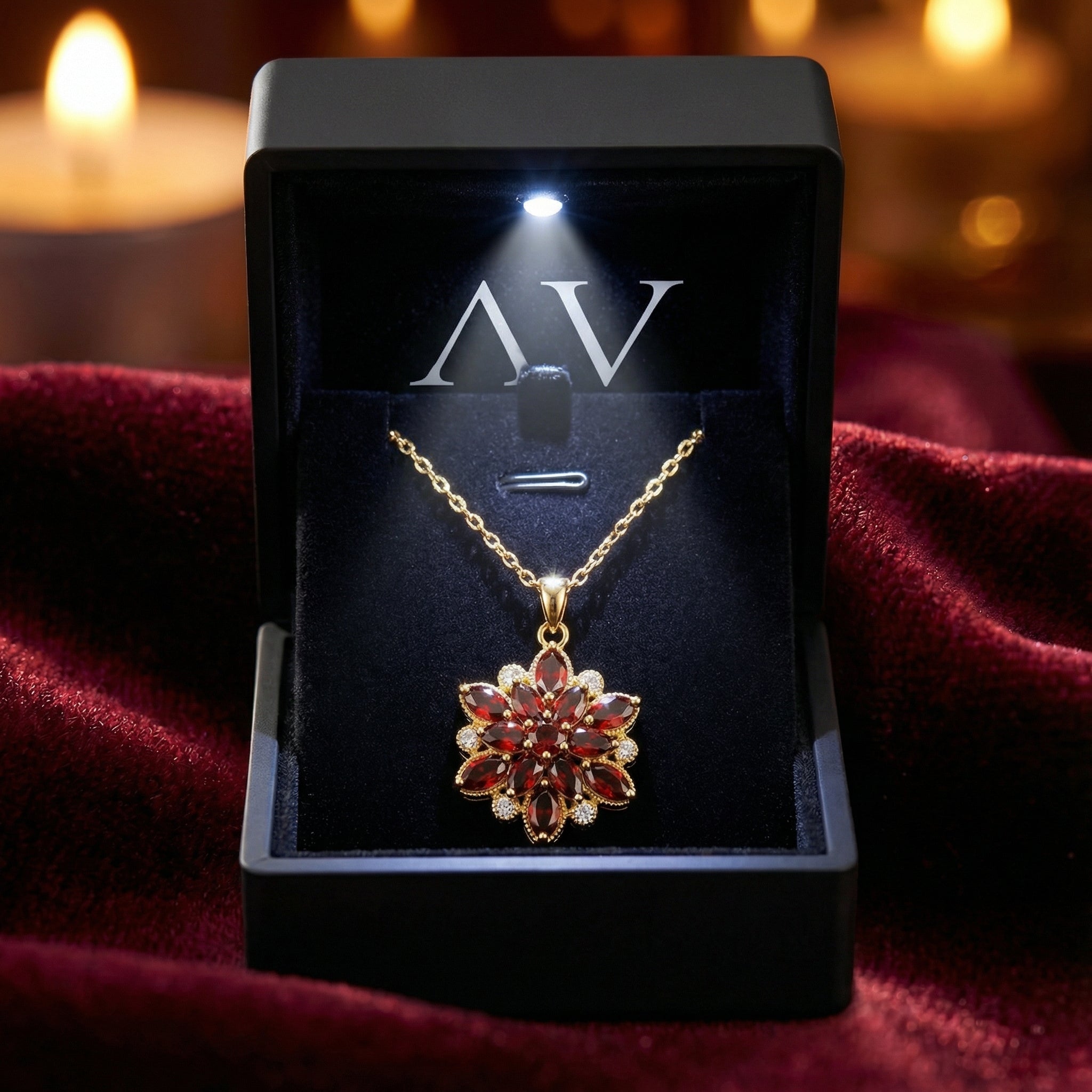 Gold finished stainless steel red garnet blossom necklace in a black LED-lighted jewelry presentation box.