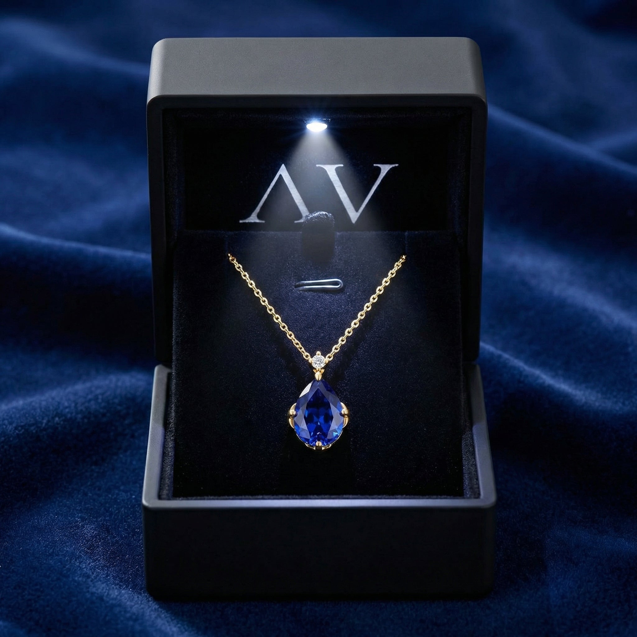 The Mariselle pear-cut simulated sapphire necklace displayed in a lighted black jewelry box.
