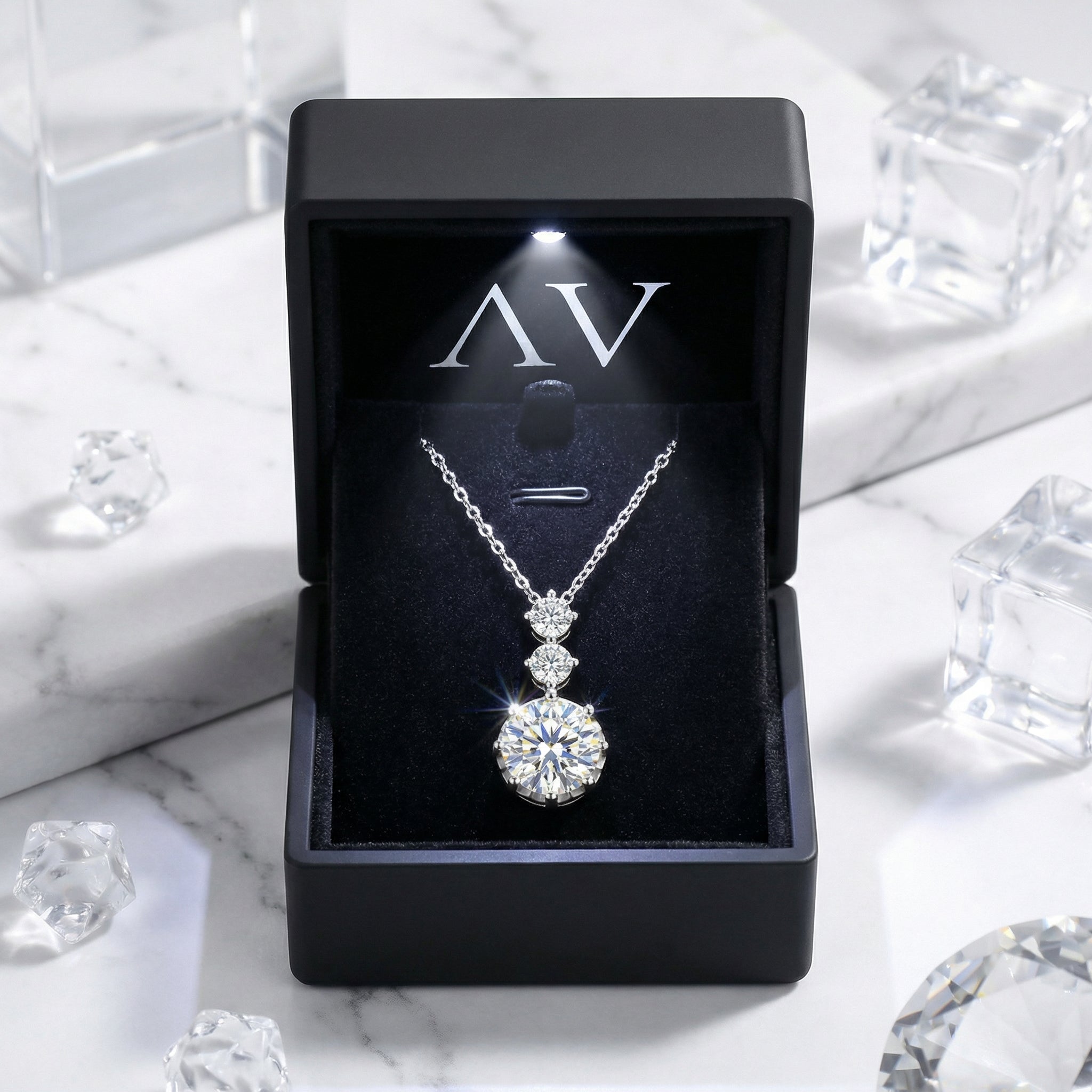 Aurelle Drop sterling silver necklace displayed in a black LED-lit jewelry gift box on a marble background.