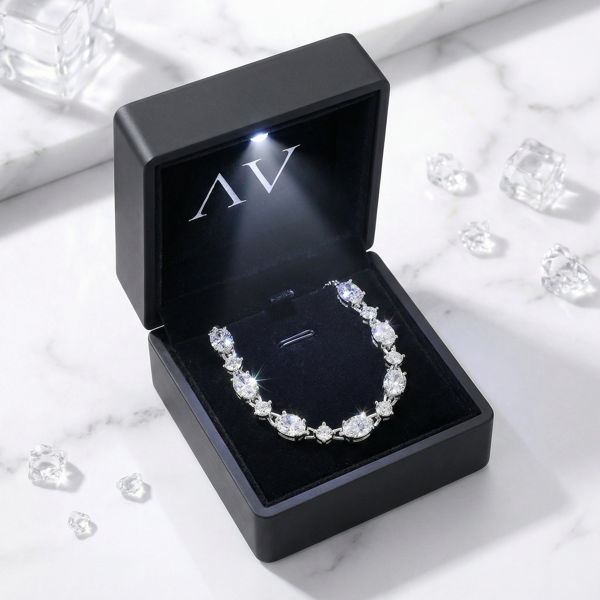 Sterling silver zirconia station bracelet inside a black LED-lit presentation box on a marble surface.