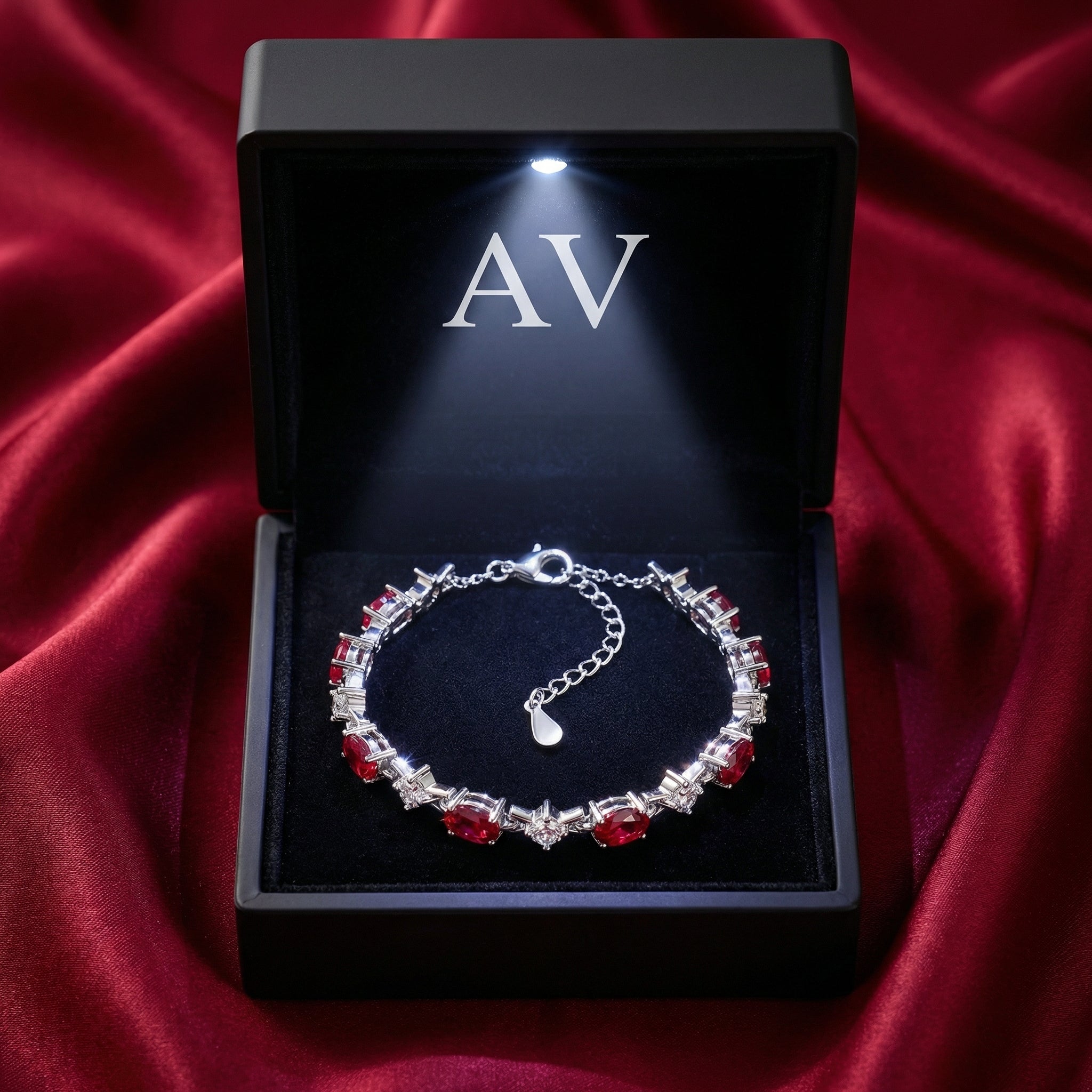 Sterling silver simulated ruby station bracelet inside a black LED-lit gift box on red satin.