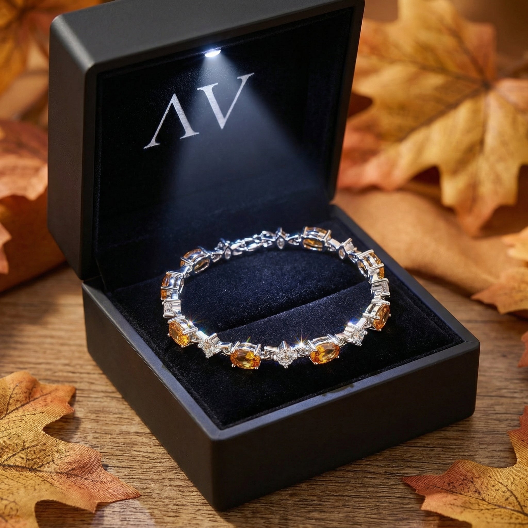 Sterling silver honeyed topaz bracelet inside a lighted black jewelry box surrounded by autumn leaves.