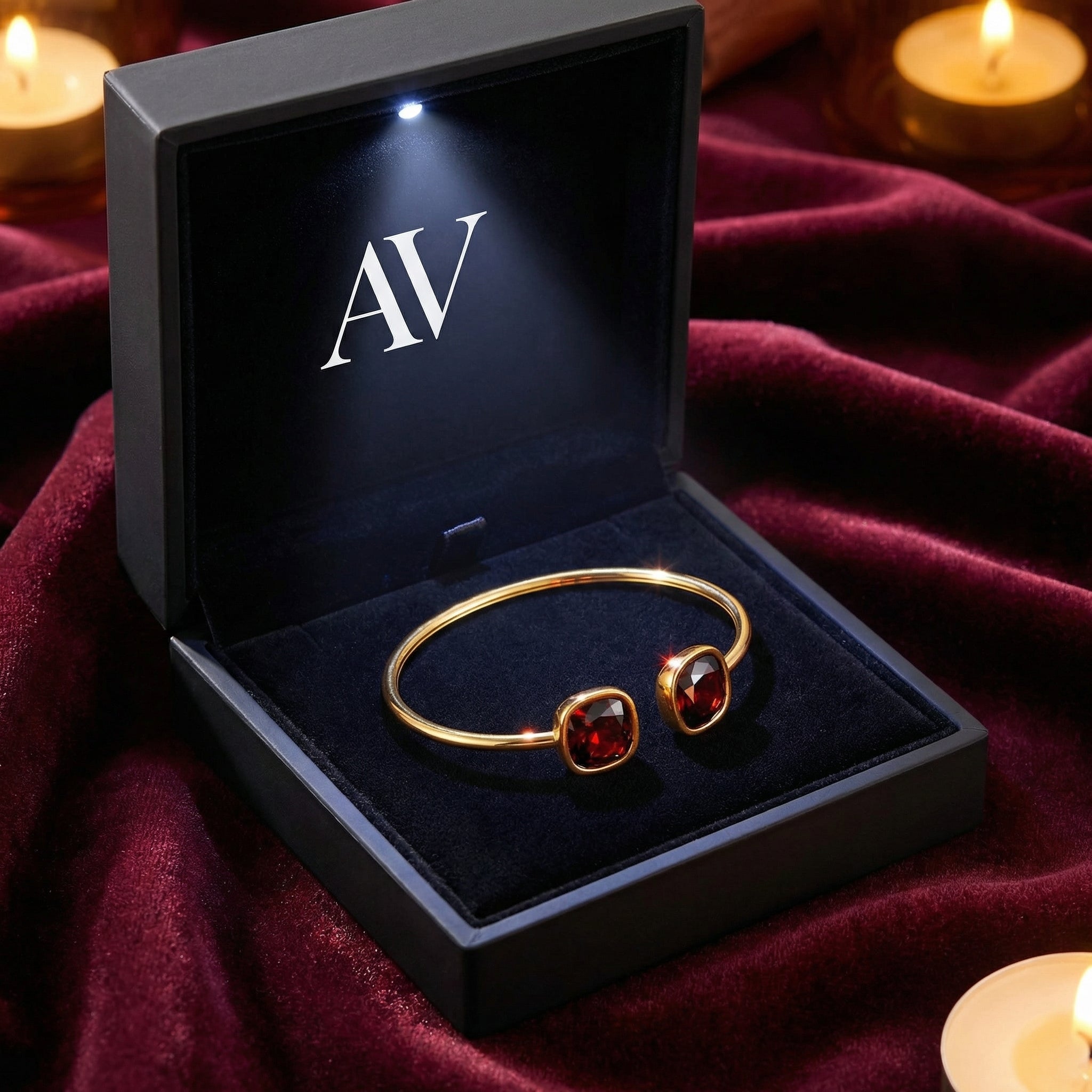 Gold stainless steel garnet bangle inside a black lighted AV jewelry box on red velvet.
