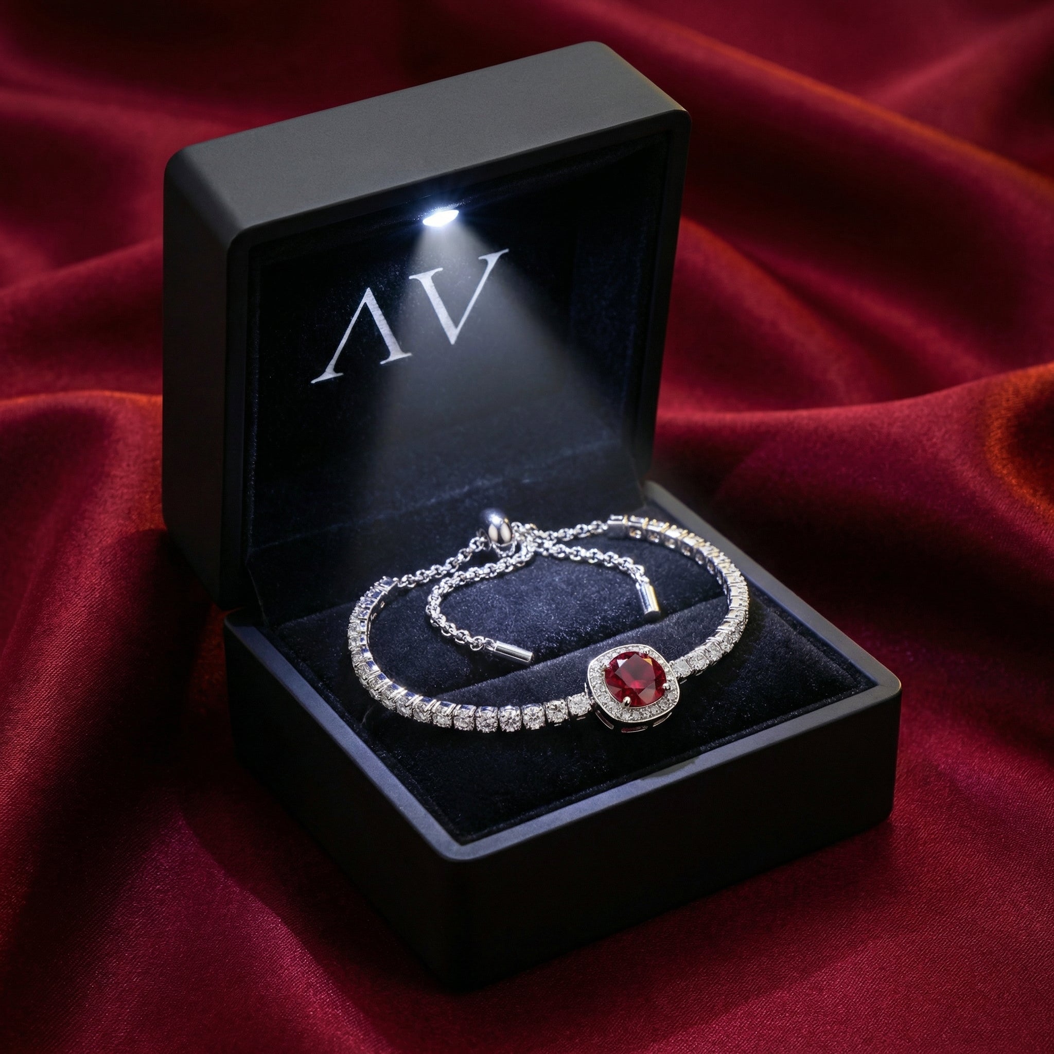 Sterling silver simulated ruby halo bracelet inside a black LED-lit jewelry gift box.