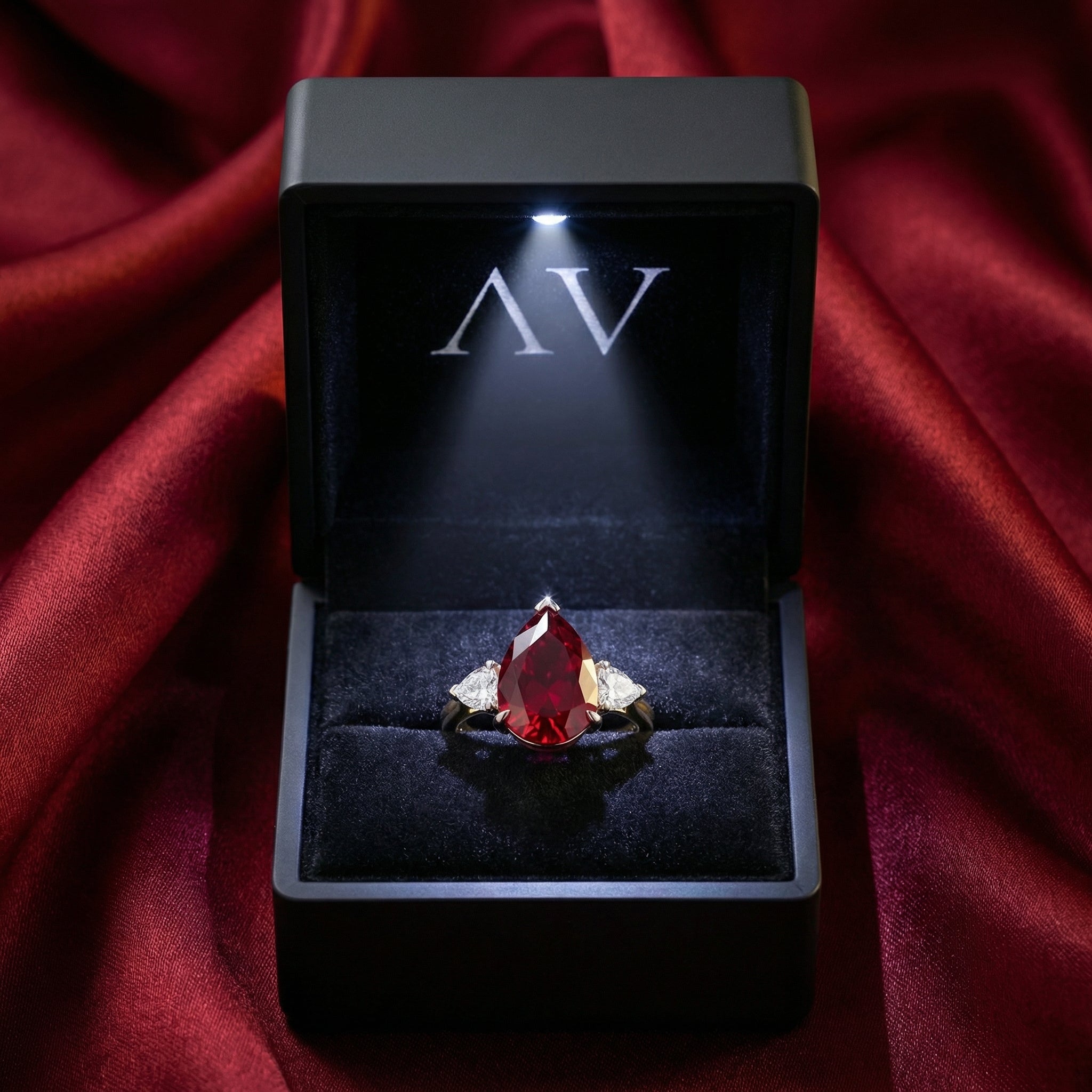 Teardrop simulated ruby ring in sterling silver inside a black LED-lighted jewelry box on red silk.