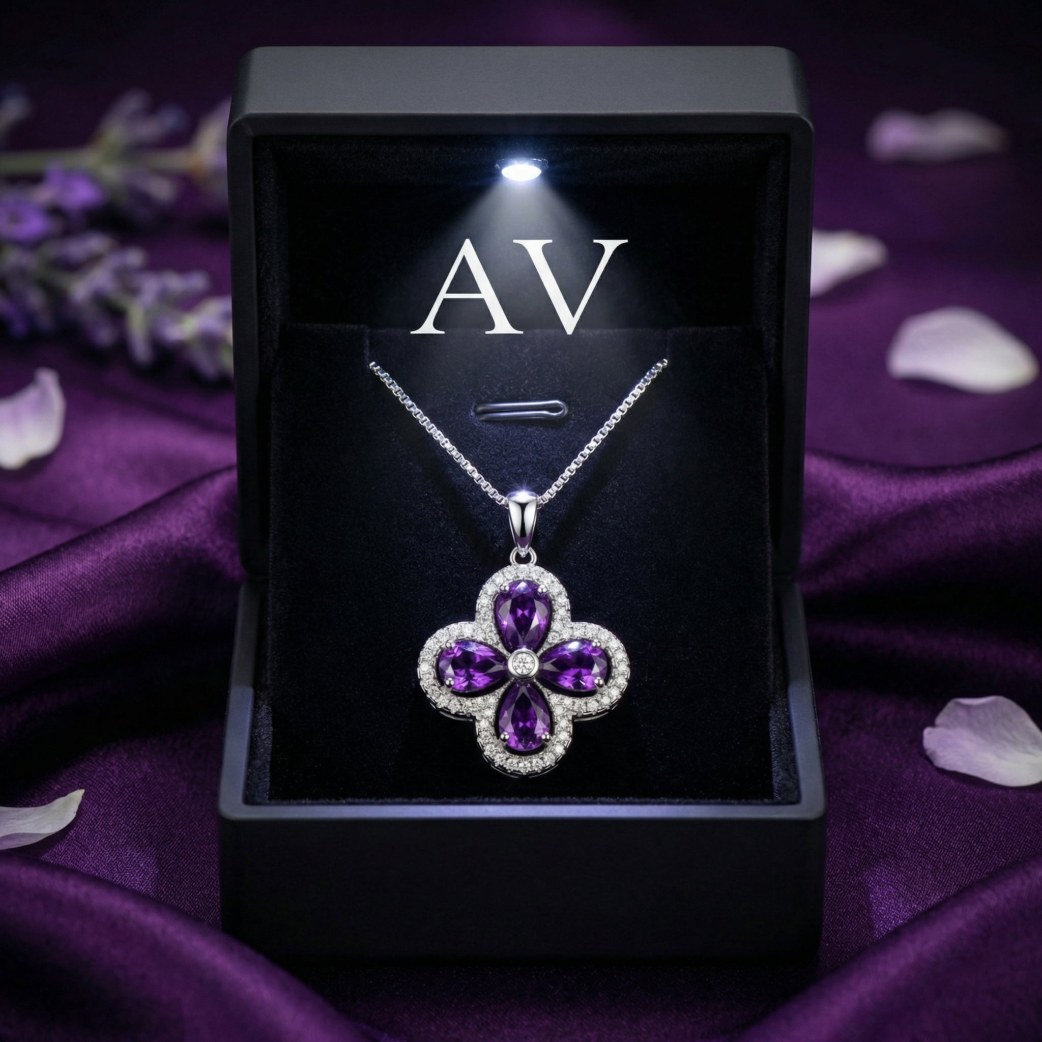 The Visteria amethyst pendant in a lighted black gift box against a purple silk background.