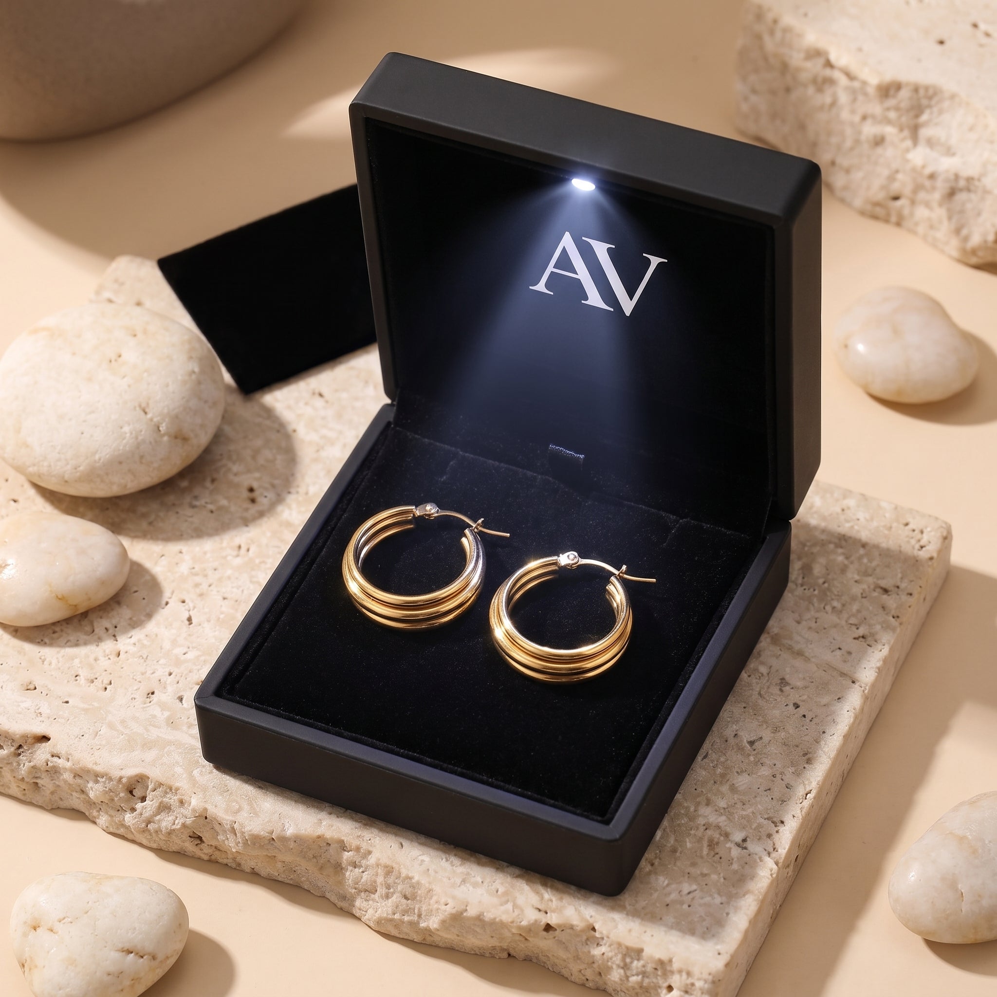 Gold triple-row woven hoop earrings inside a black LED-lit gift box.