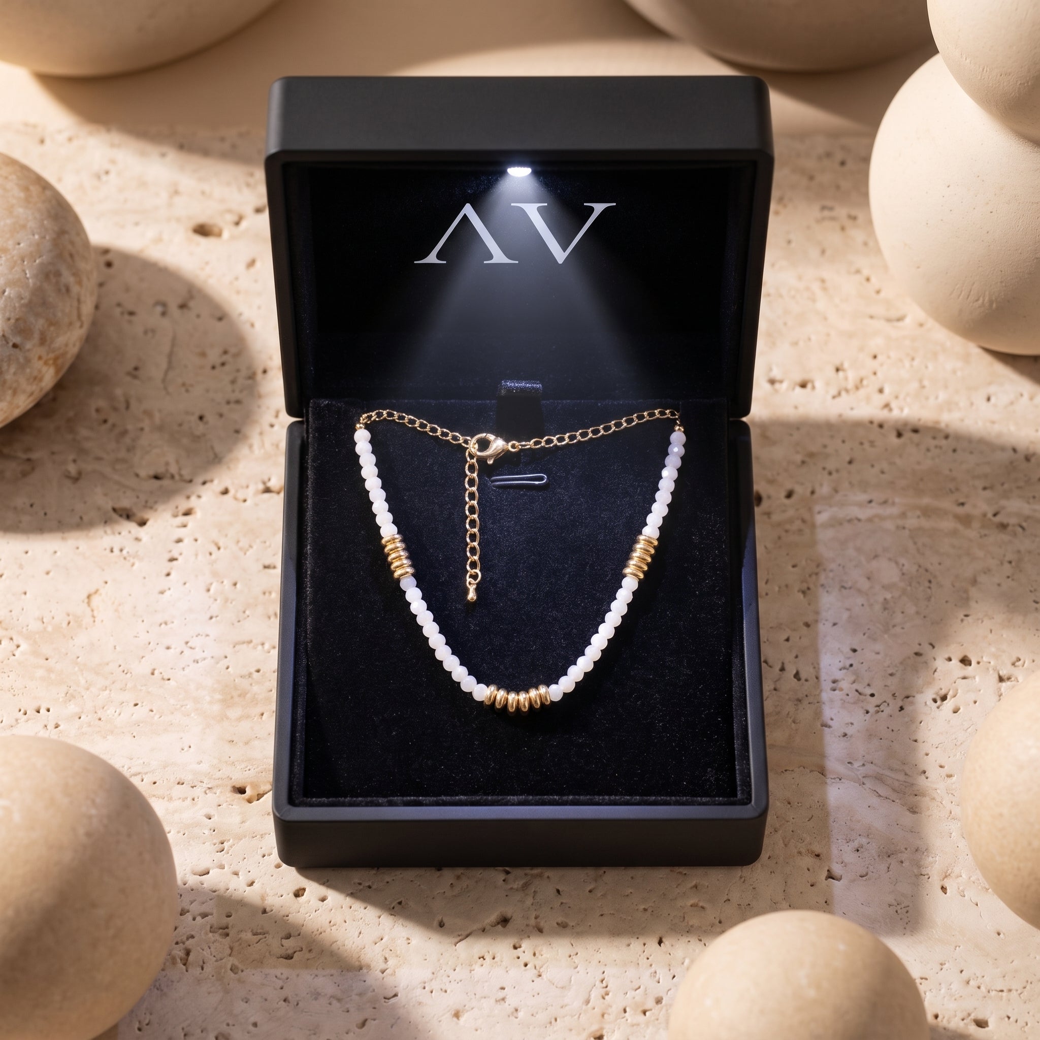 White quartz beaded necklace with gold accents inside a lighted black jewelry gift box.