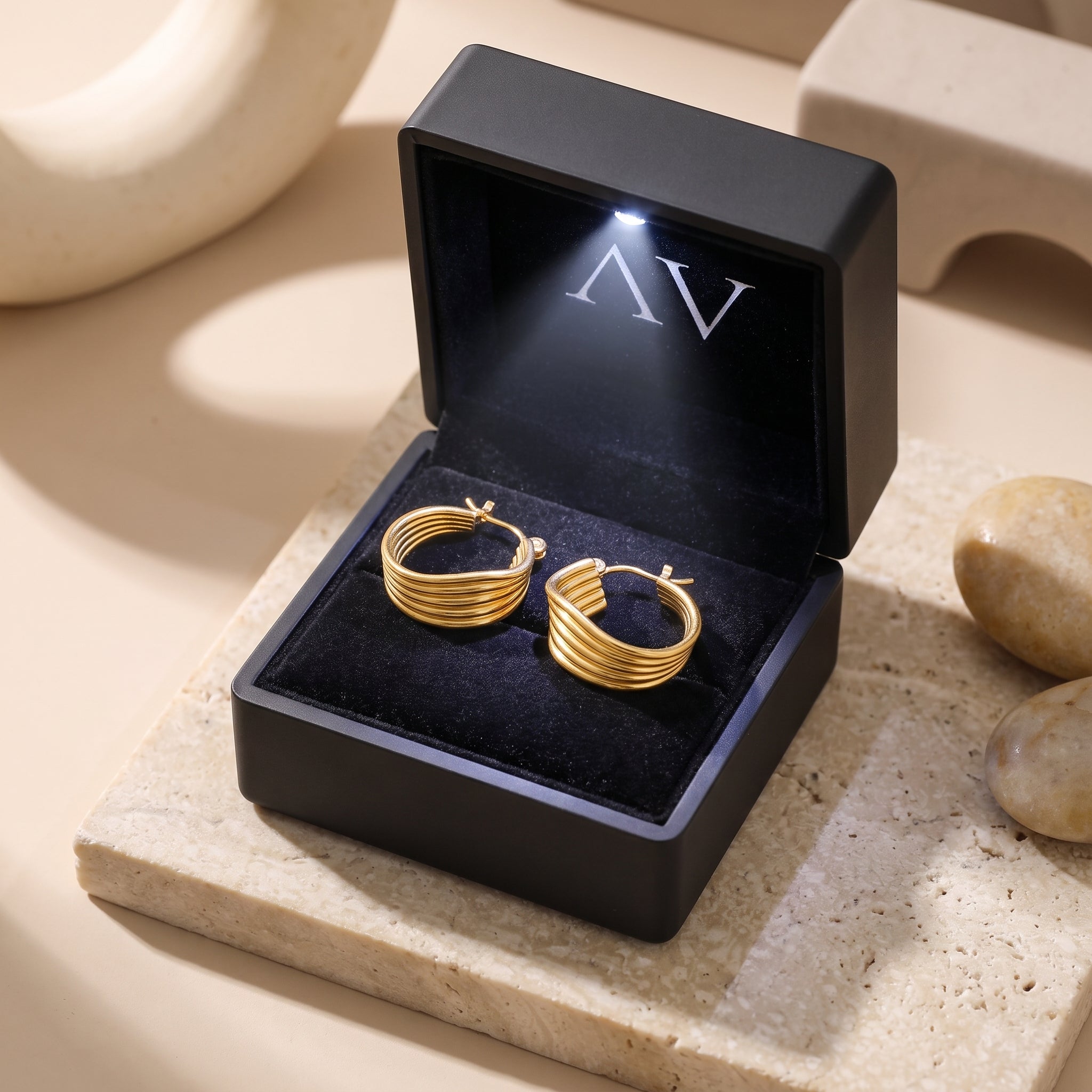 Gold Isolina hoop earrings in a black LED-lighted gift box.