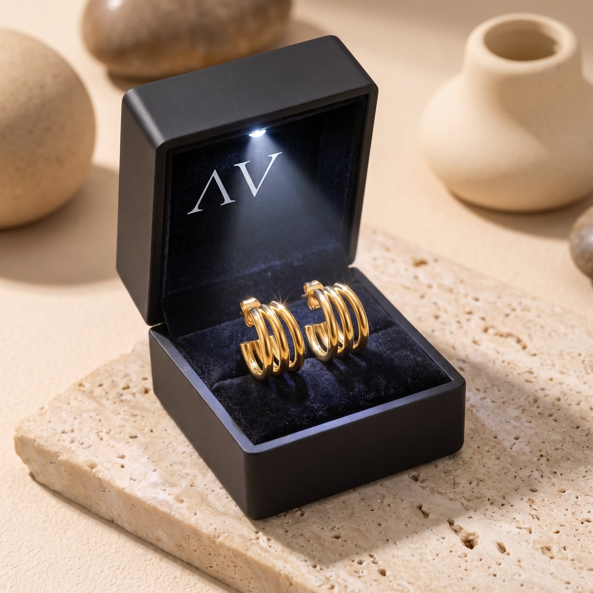 Gold triple-band hoop earrings inside a black LED-lit gift box.