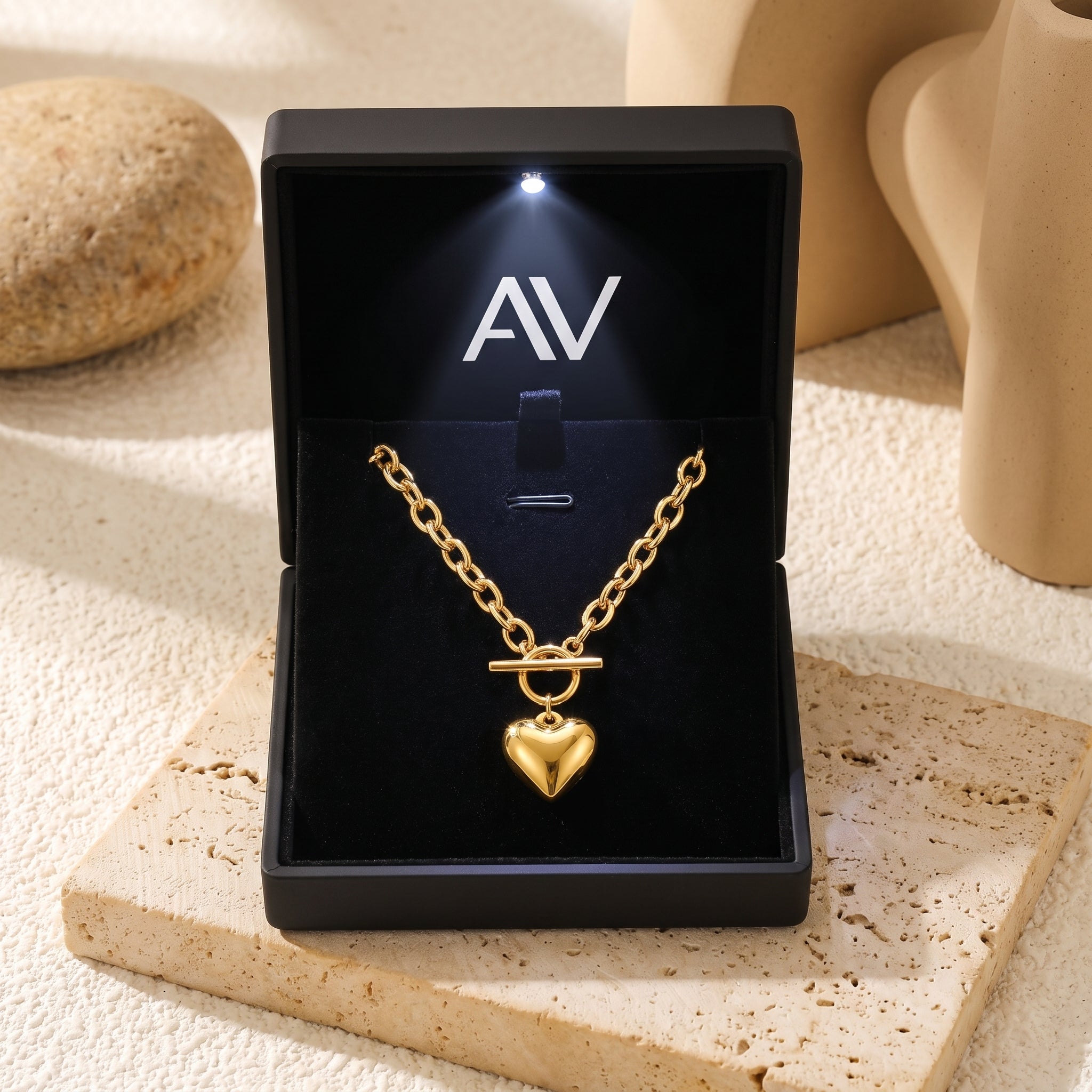 Gold heart pendant necklace inside a black LED-lit jewelry gift box.