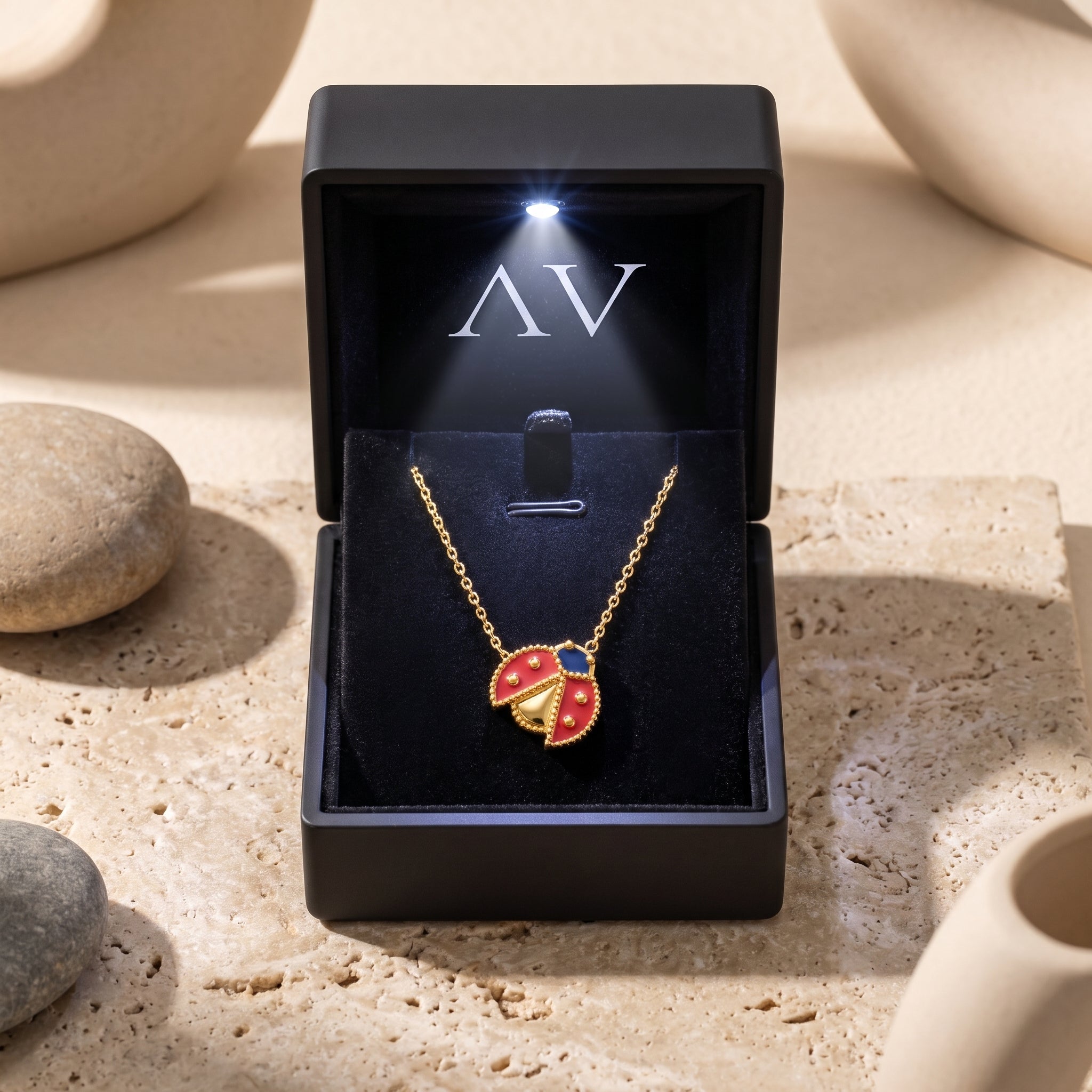 Gold ladybug necklace presented in a black LED-lit gift box.