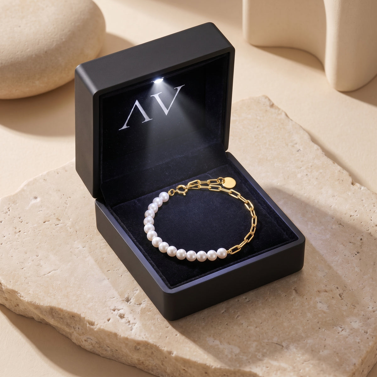 Solid gold and pearl bracelet presented in a black illuminated jewelry gift box.