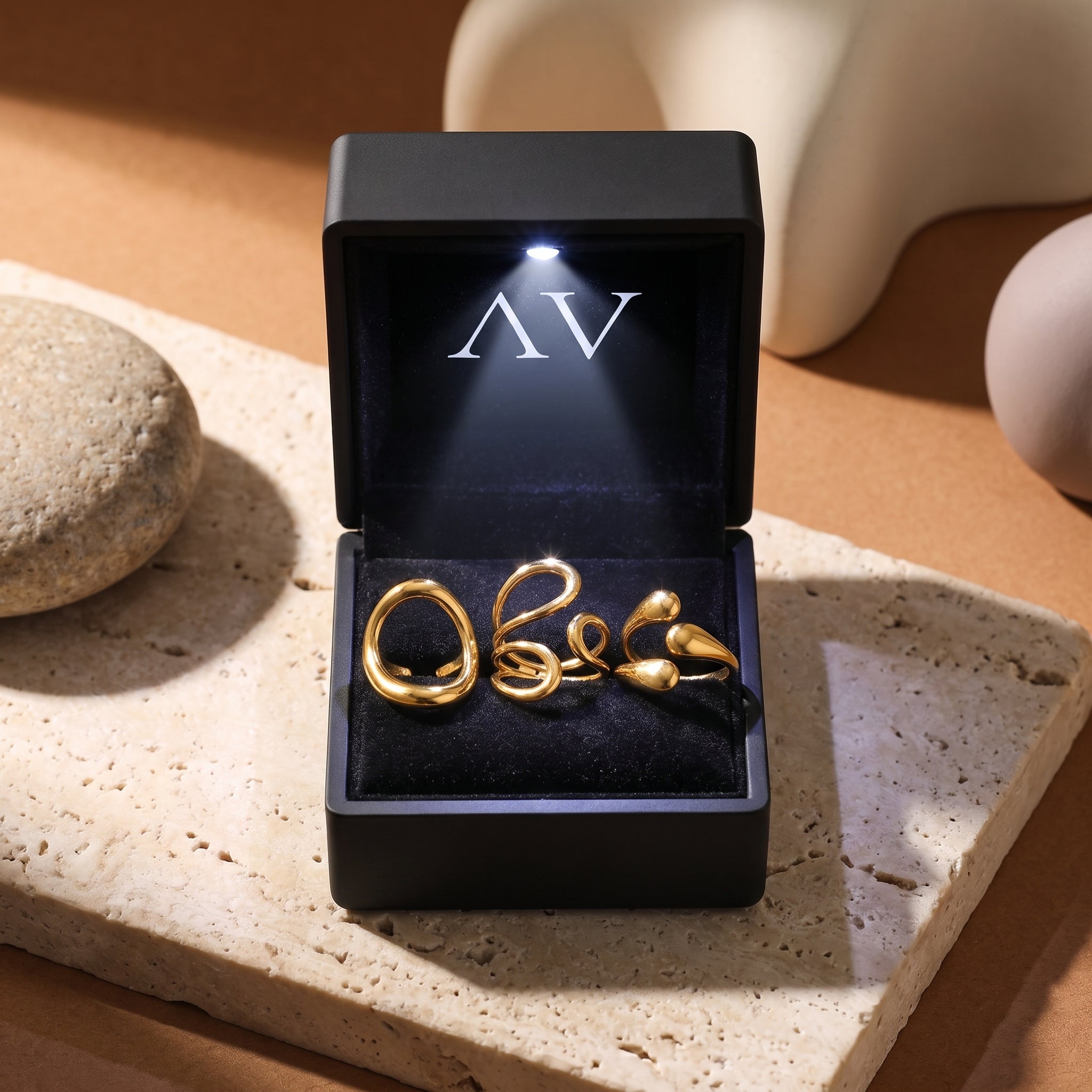 Three gold adjustable rings inside a black LED-lit jewelry box.