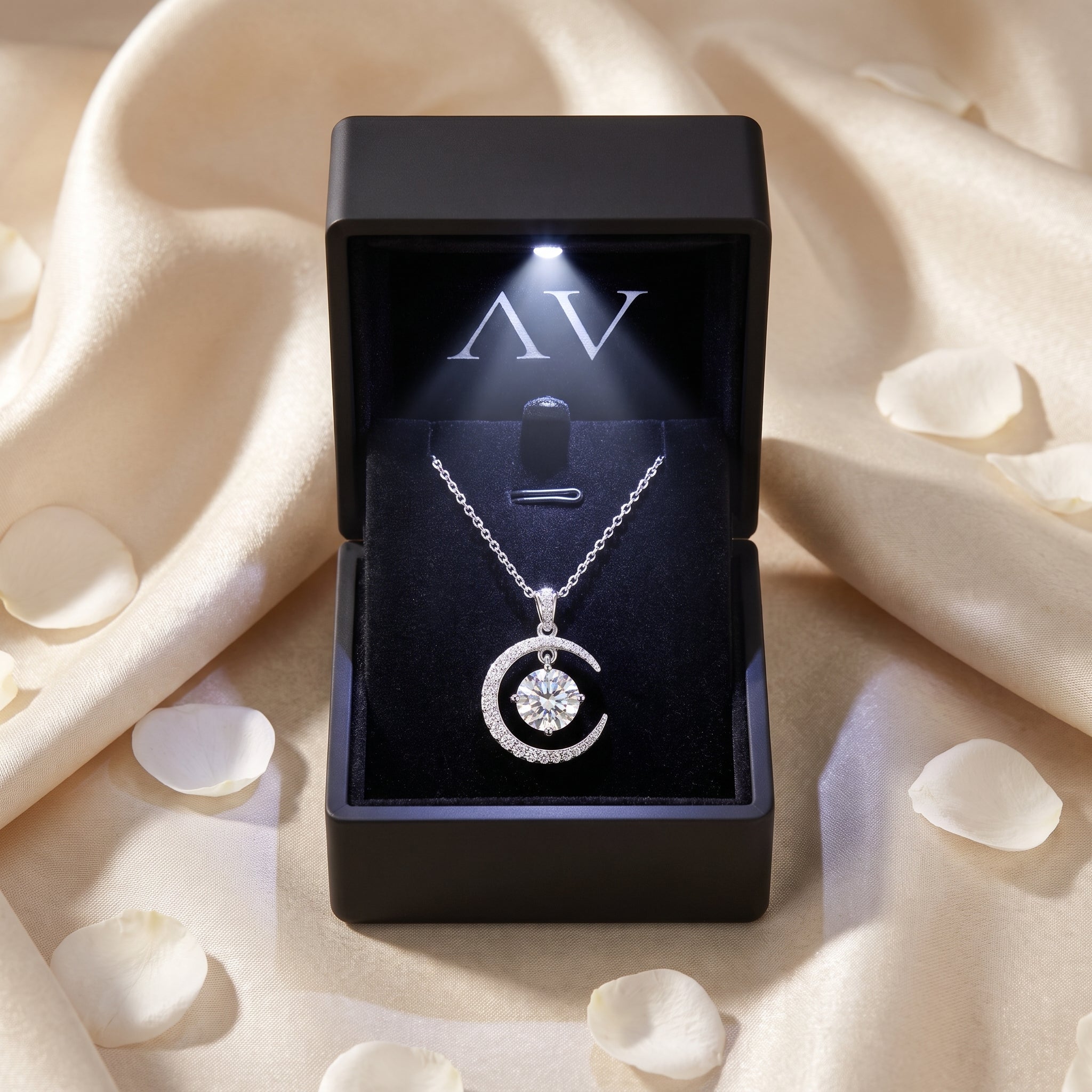 Silver moissanite crescent moon necklace in a black LED-lit gift box.