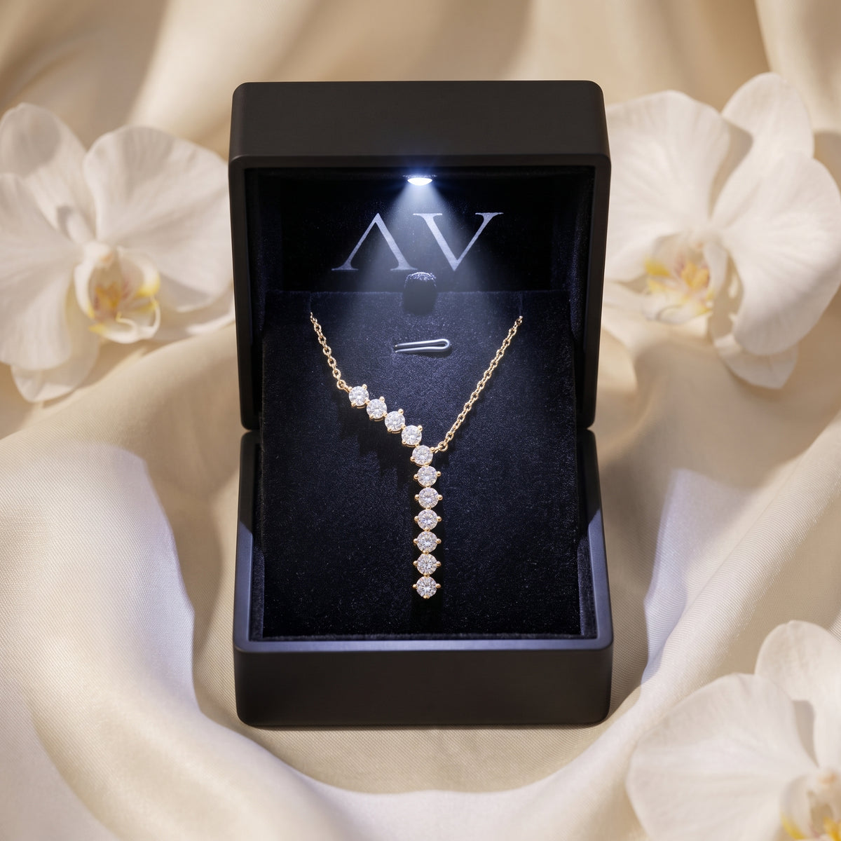 Gold curved drop moissanite necklace presented in a black LED-lit jewelry gift box.