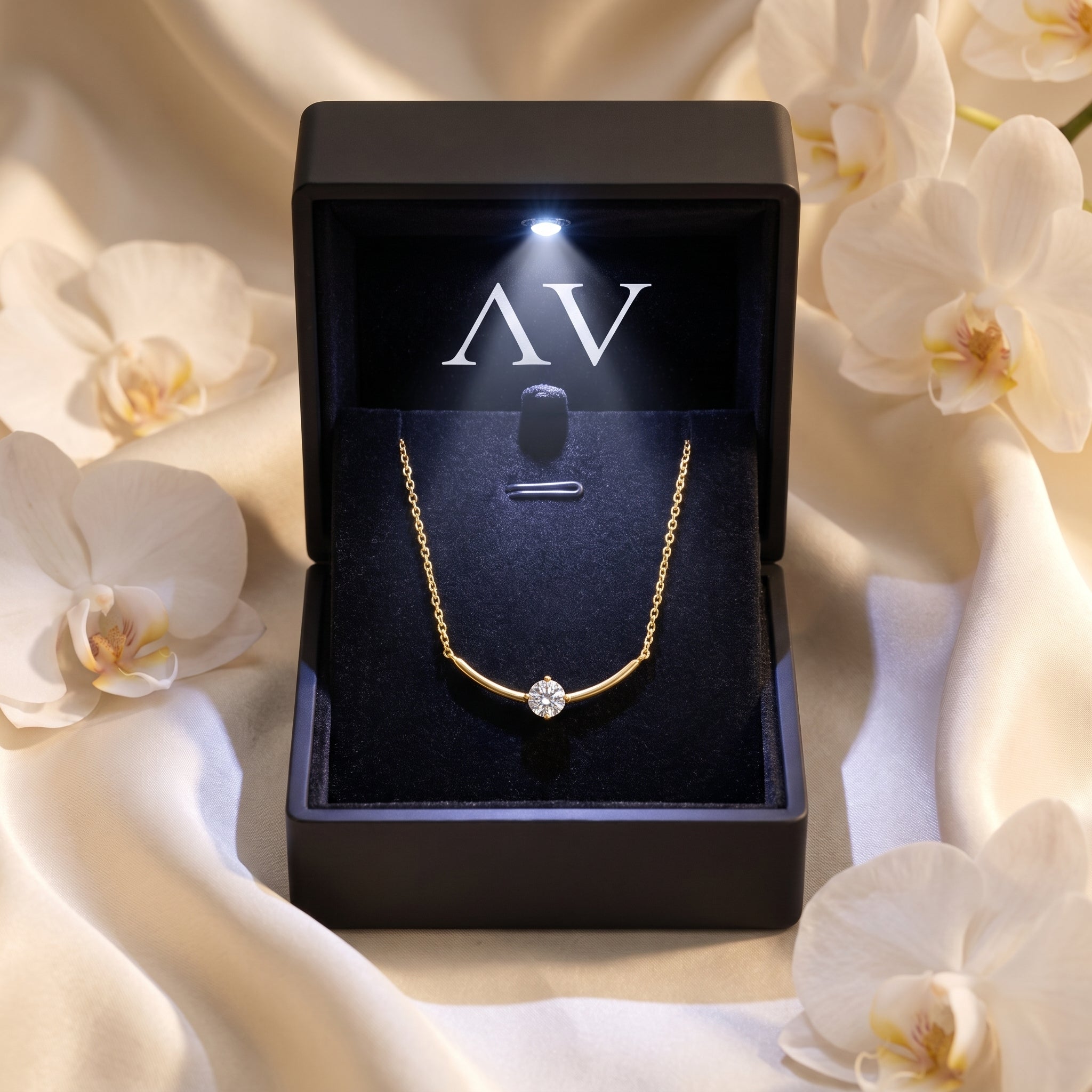 Gold Elionara moissanite necklace presented in a black LED-lit gift box with white orchid accents.