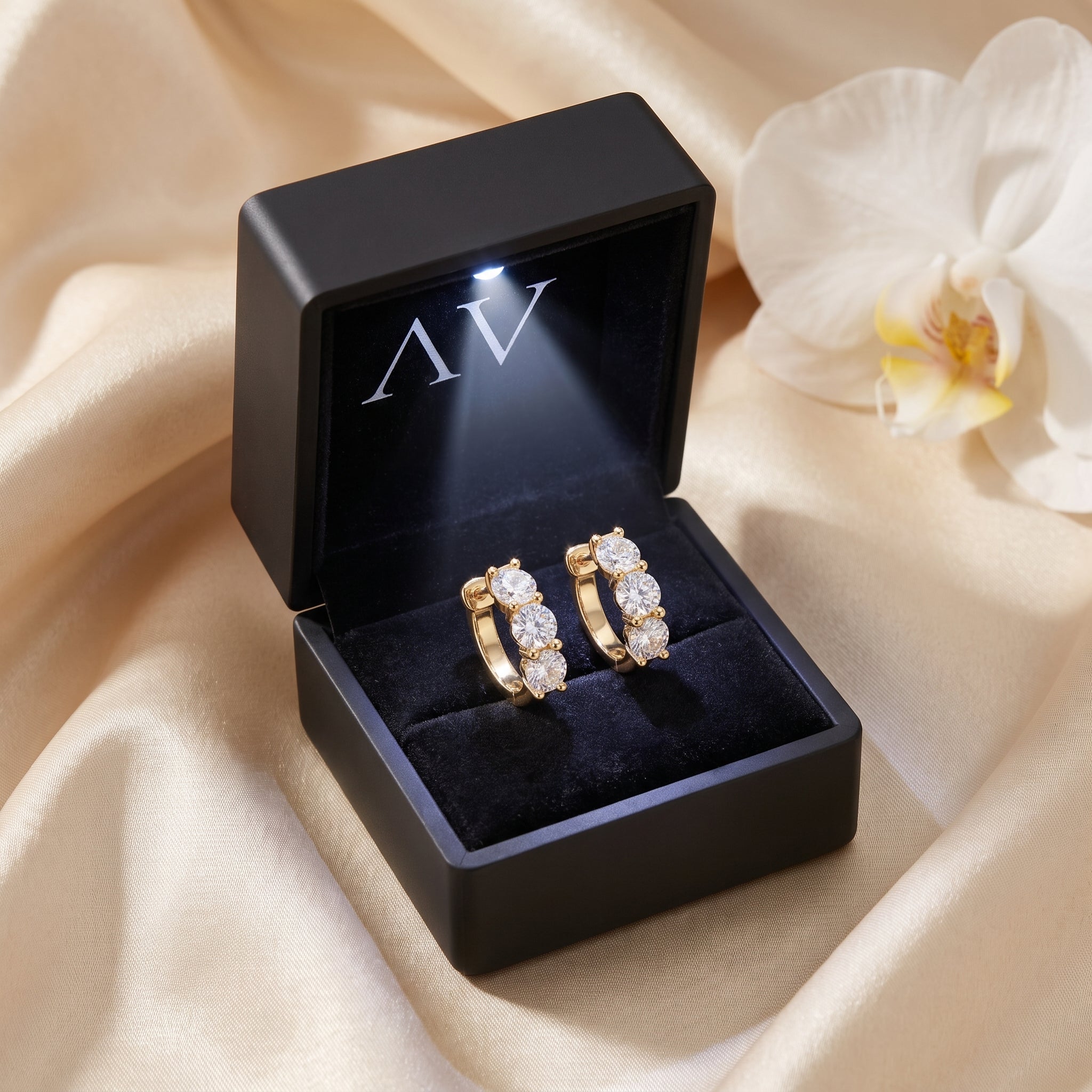 Gold moissanite hoop earrings presented in a black LED-lit jewelry gift box.