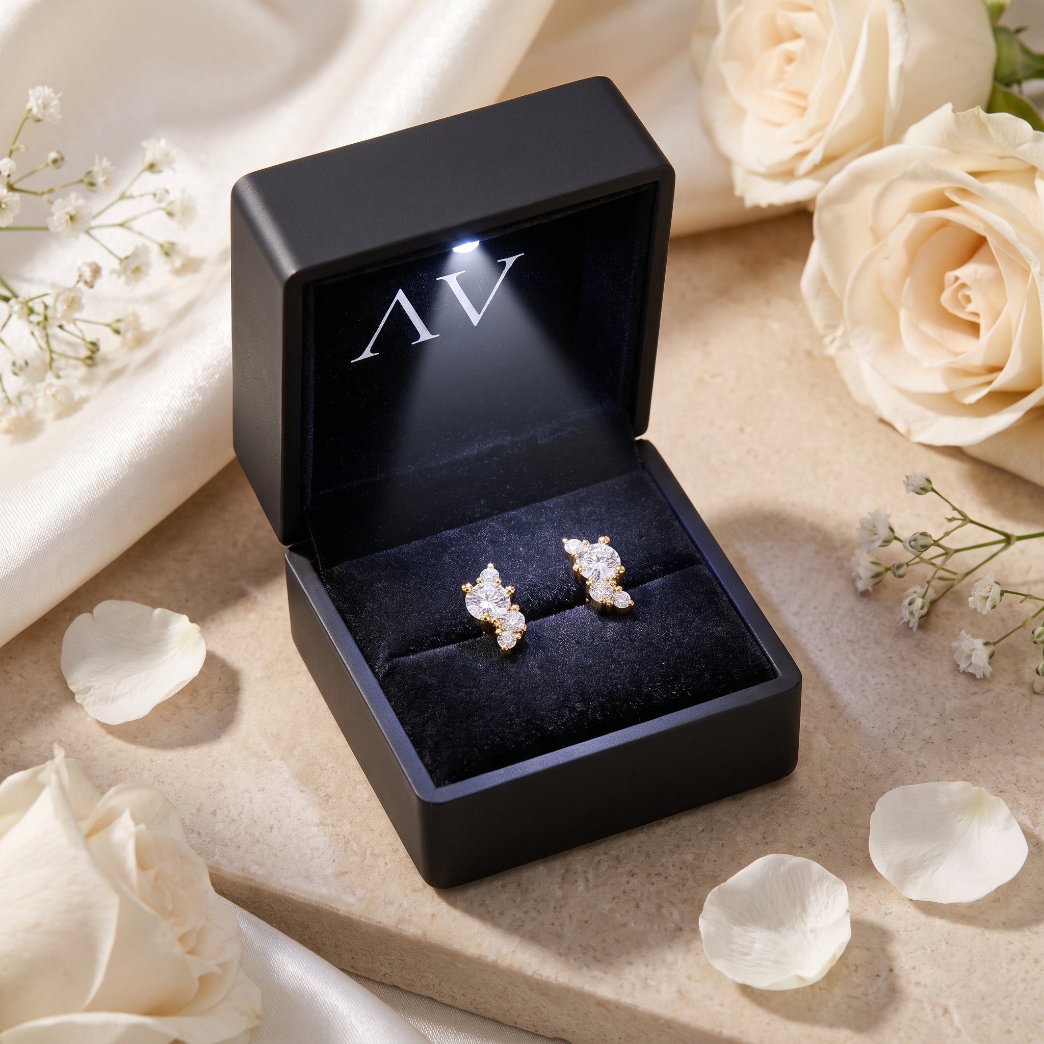 Gold moissanite cluster earrings in a black LED-lit gift box with white roses.